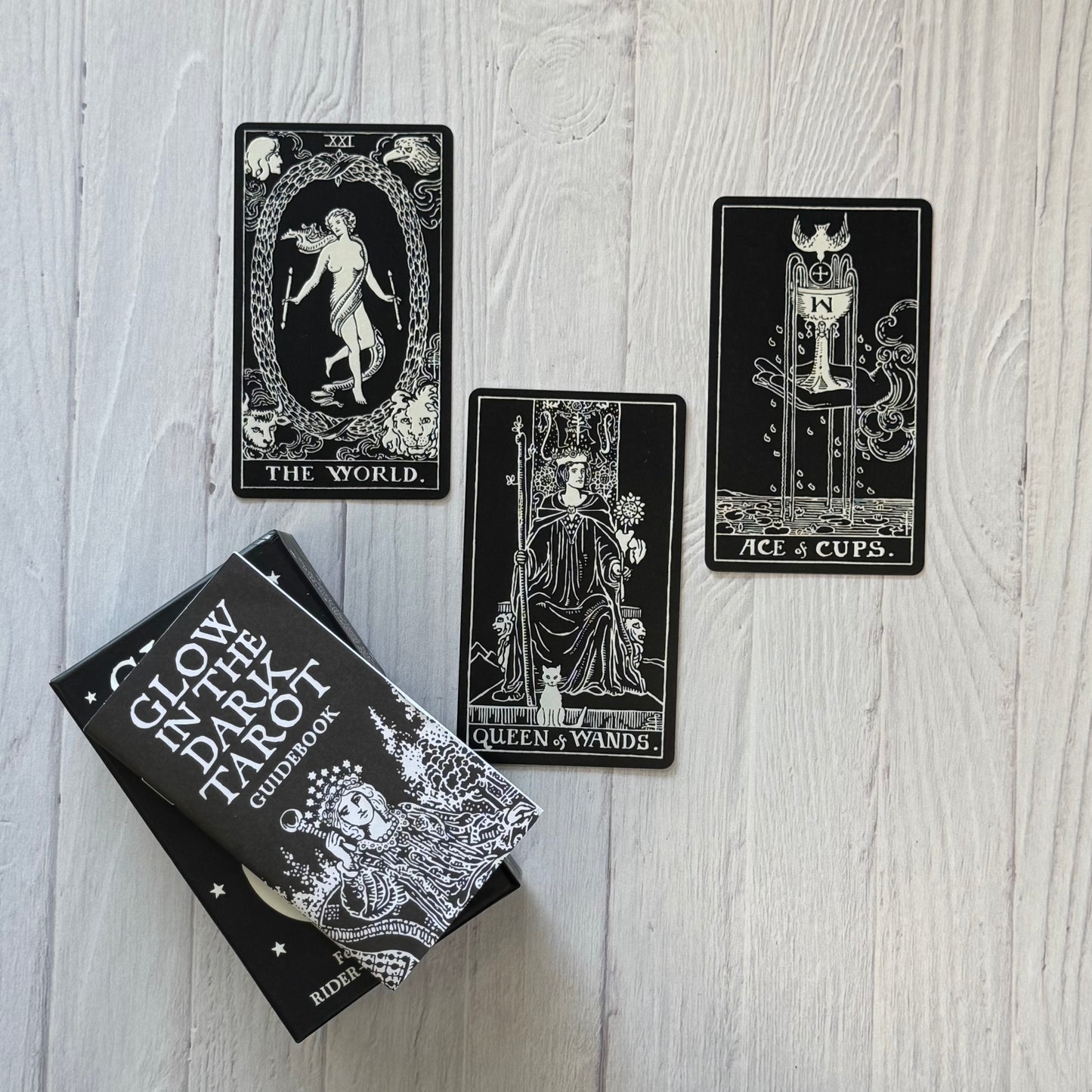 Glow in the Dark Tarot cards with their guidebook on a wooden surface