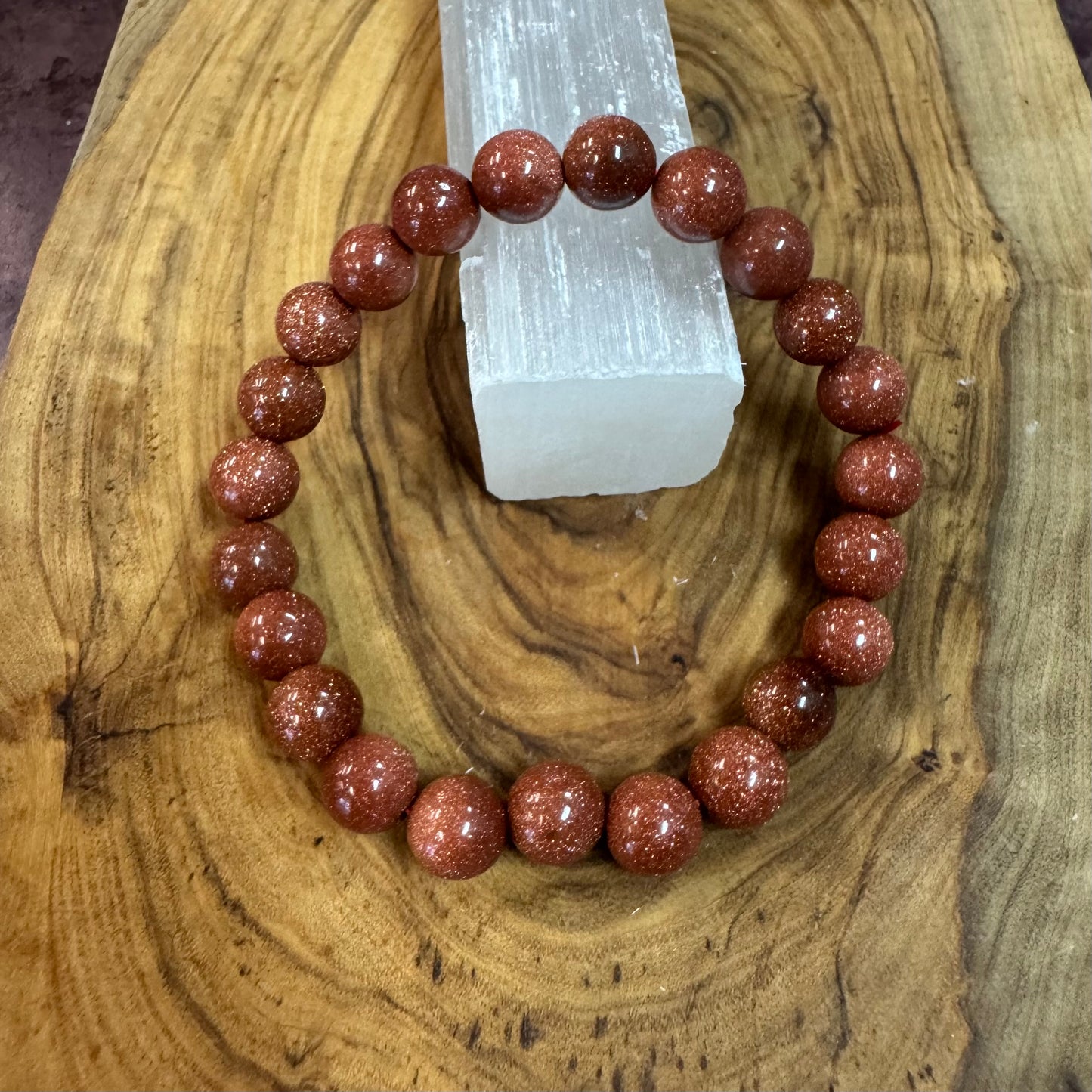 Red gemstone bracelet on a wooden surface with a crystal in the background