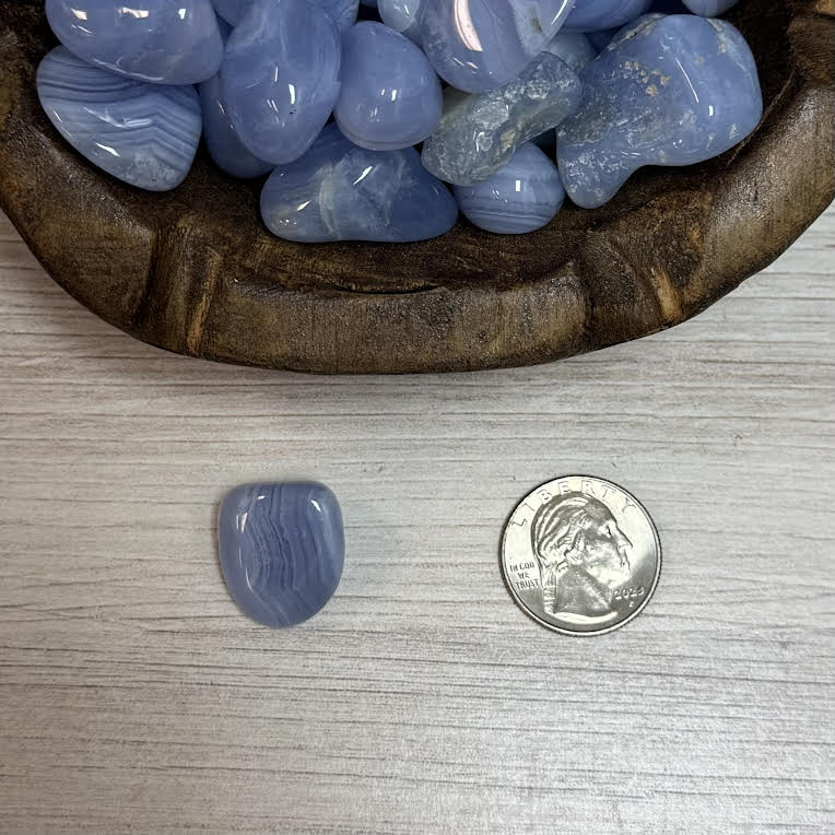 Blue stone next to a quarter on a wooden surface
