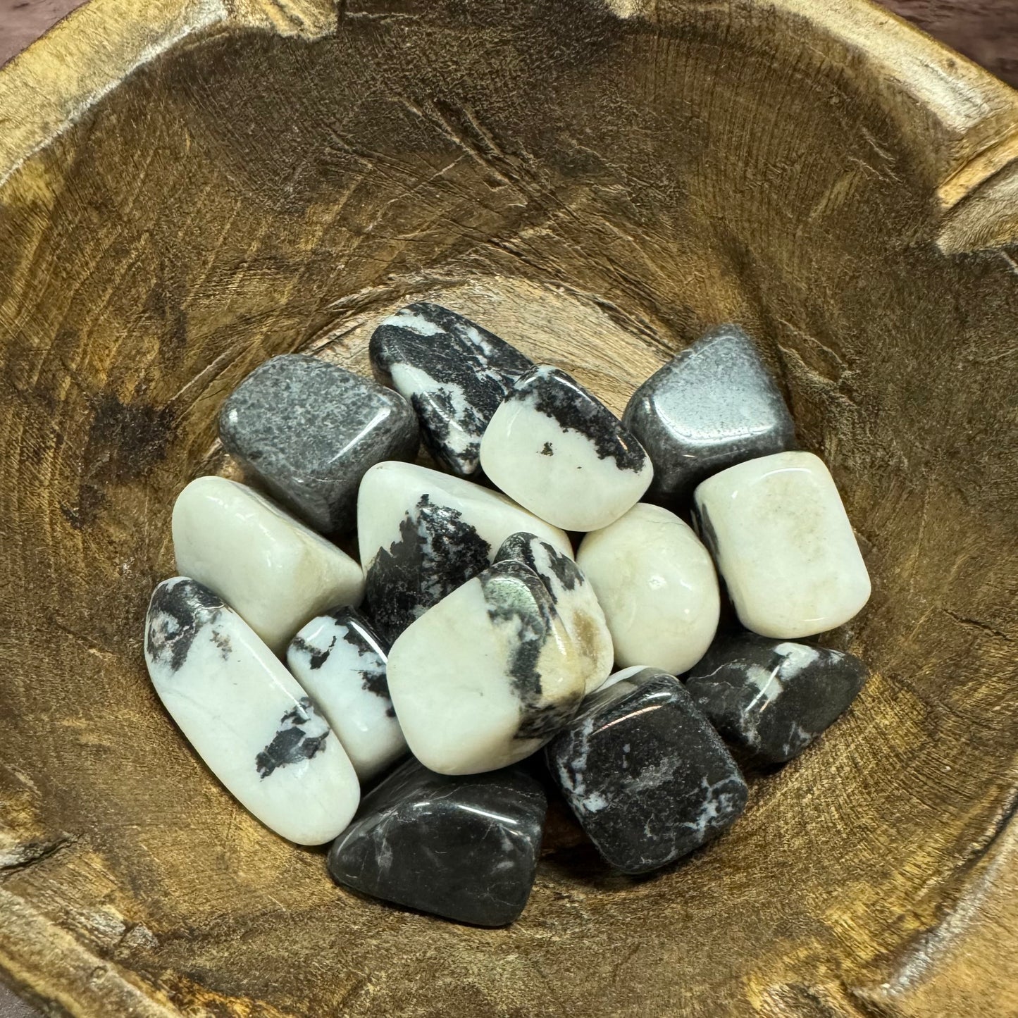 Collection of black and white stones in a wooden bowl