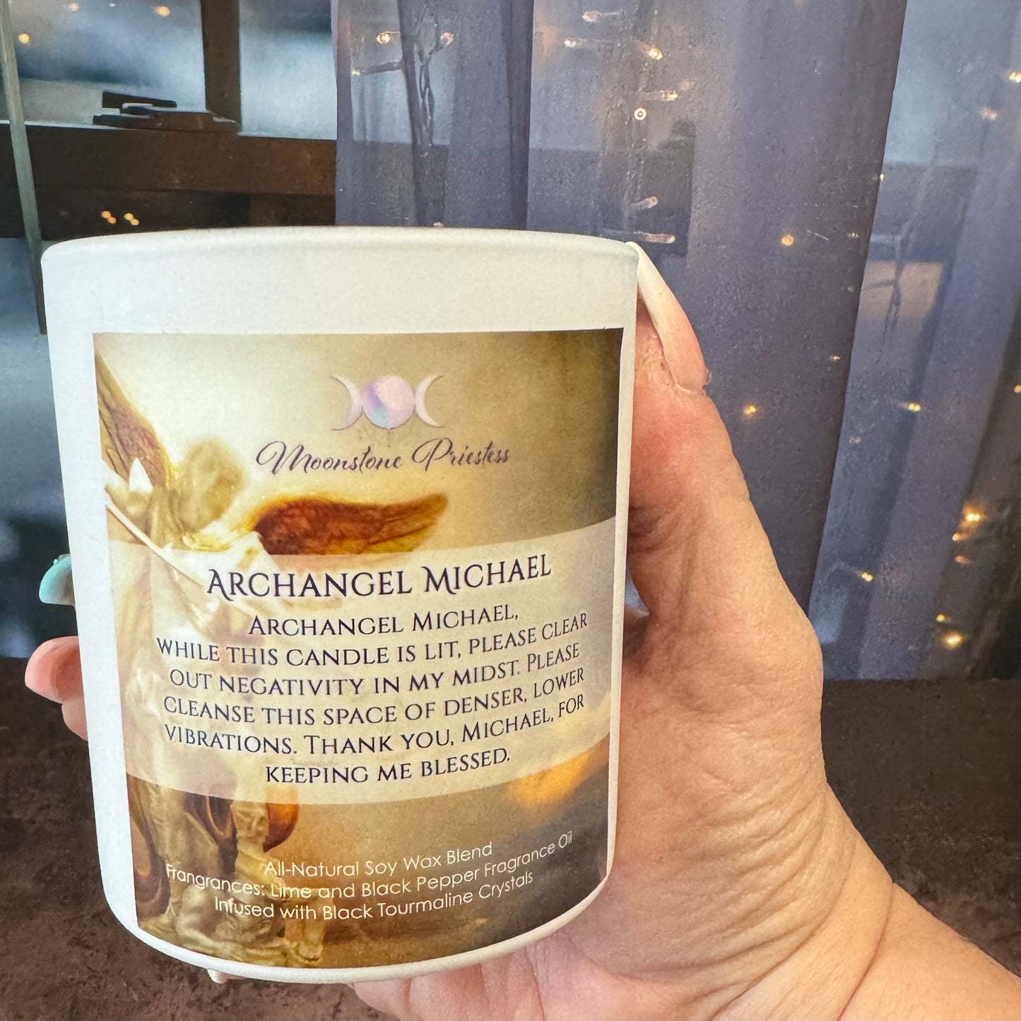 Hand holding a candle labeled 'Archangel Michael' with a blurred background
