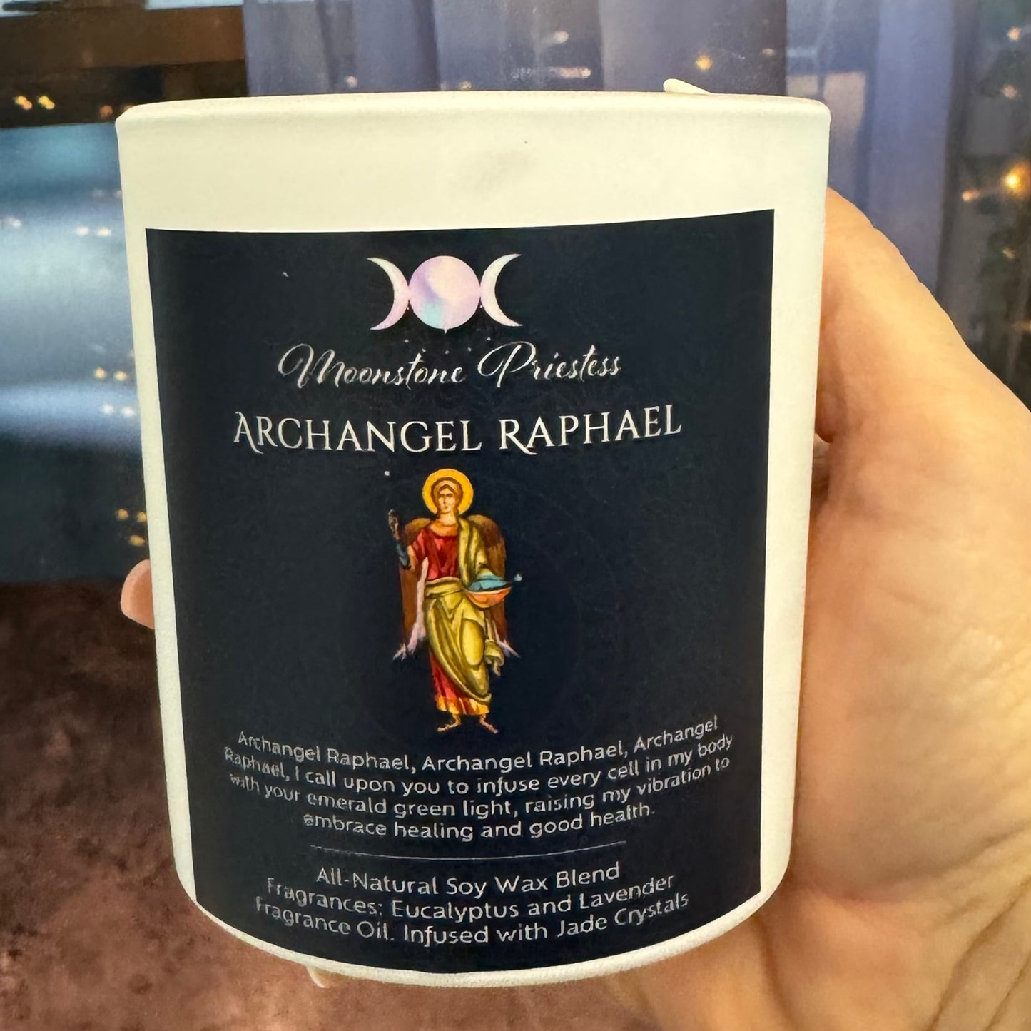 Candle labeled 'Archangel Raphael' held by a hand with a blurred background