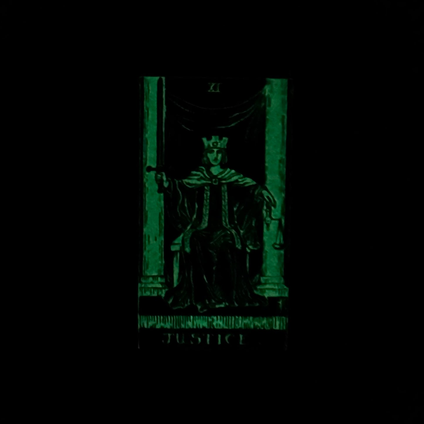 Tarot card featuring a figure named 'Justice' with a green glow on a black background