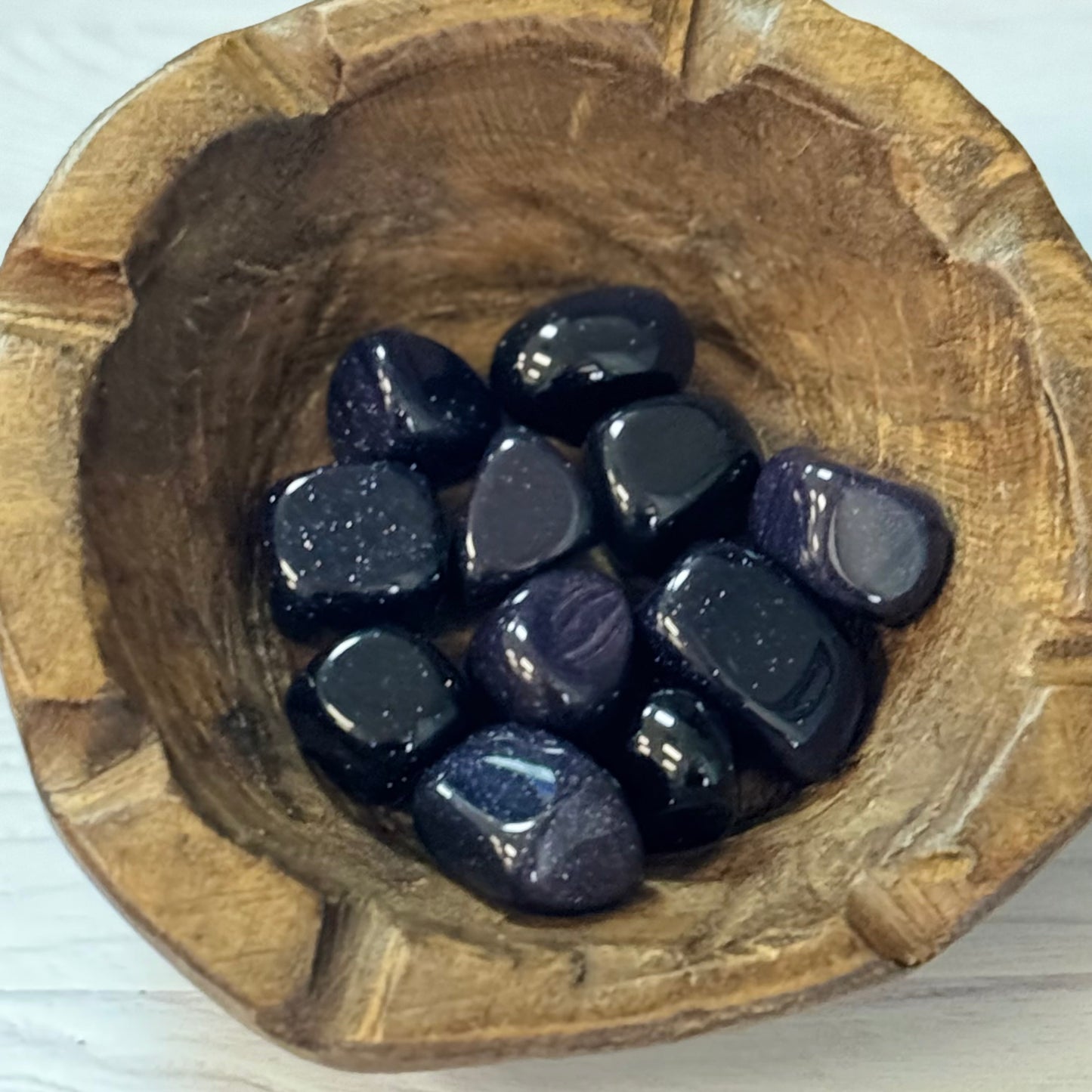 Wooden bowl with purple stones on a white background