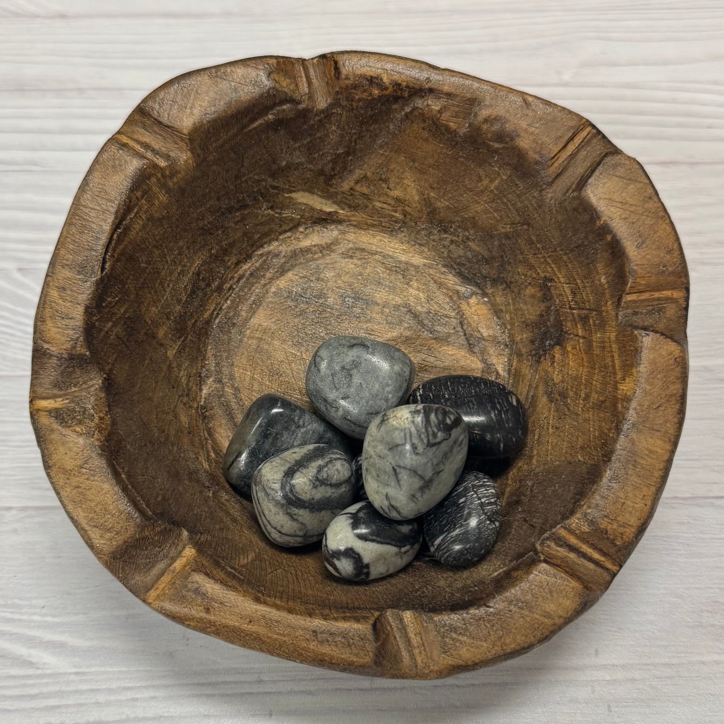 Wooden bowl with stones on a white background