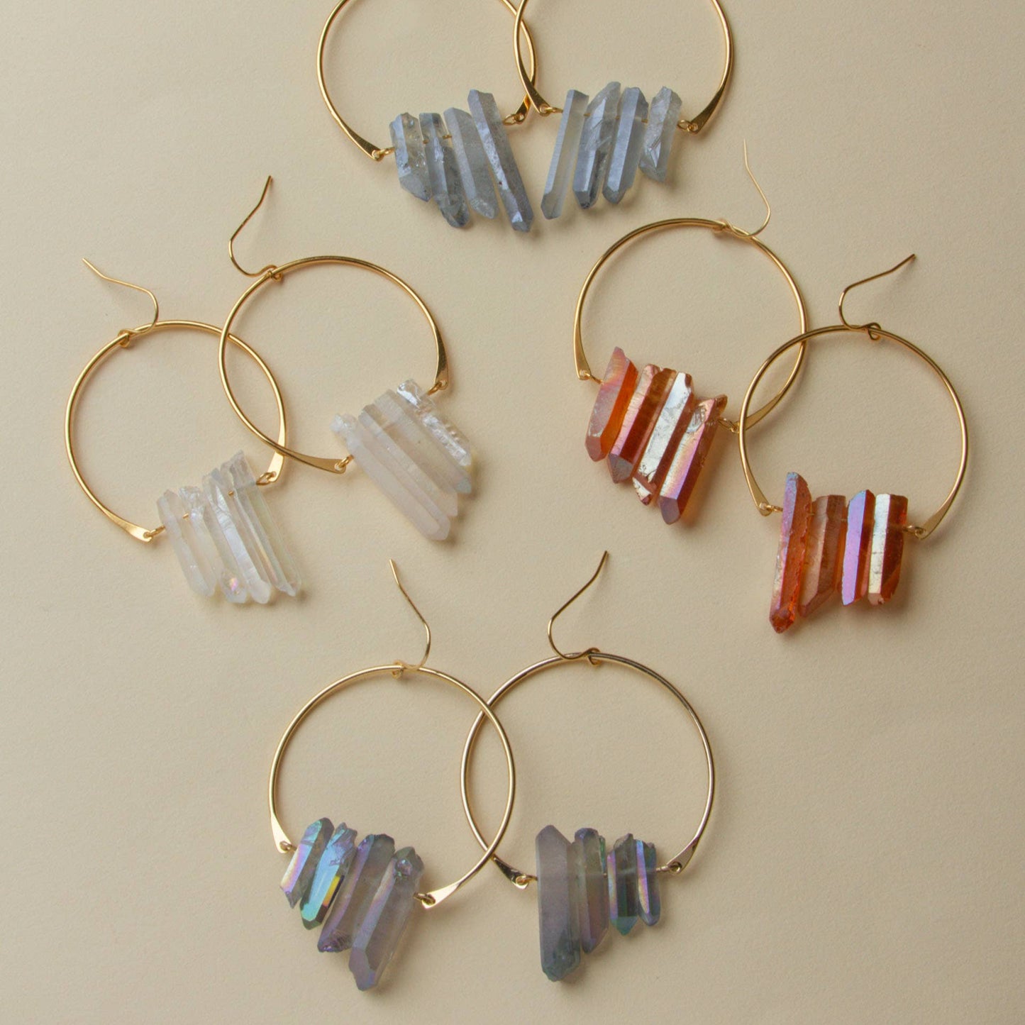 Gold hoop earrings with colorful stone beads on a beige background