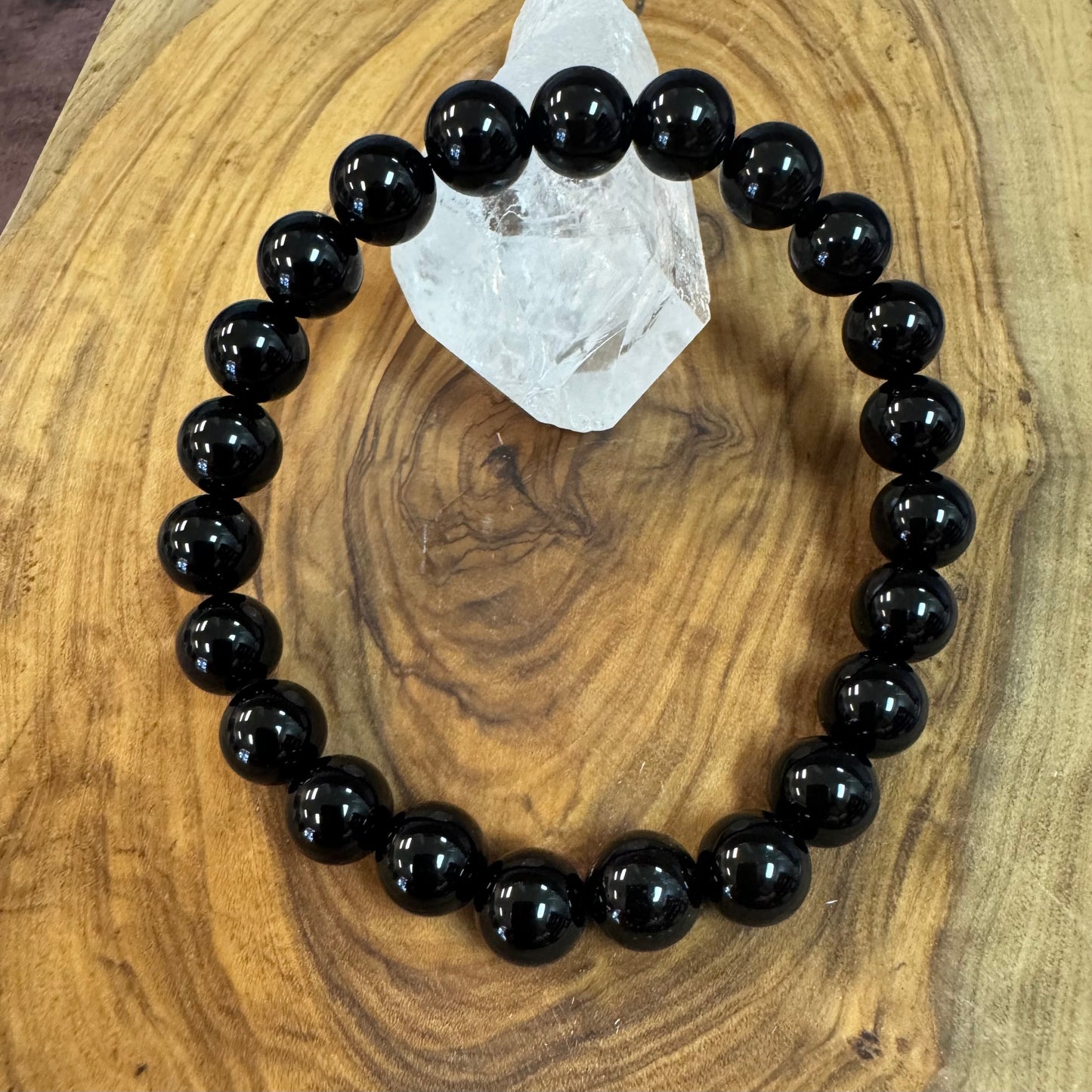 Black beaded bracelet on a wooden surface with a crystal