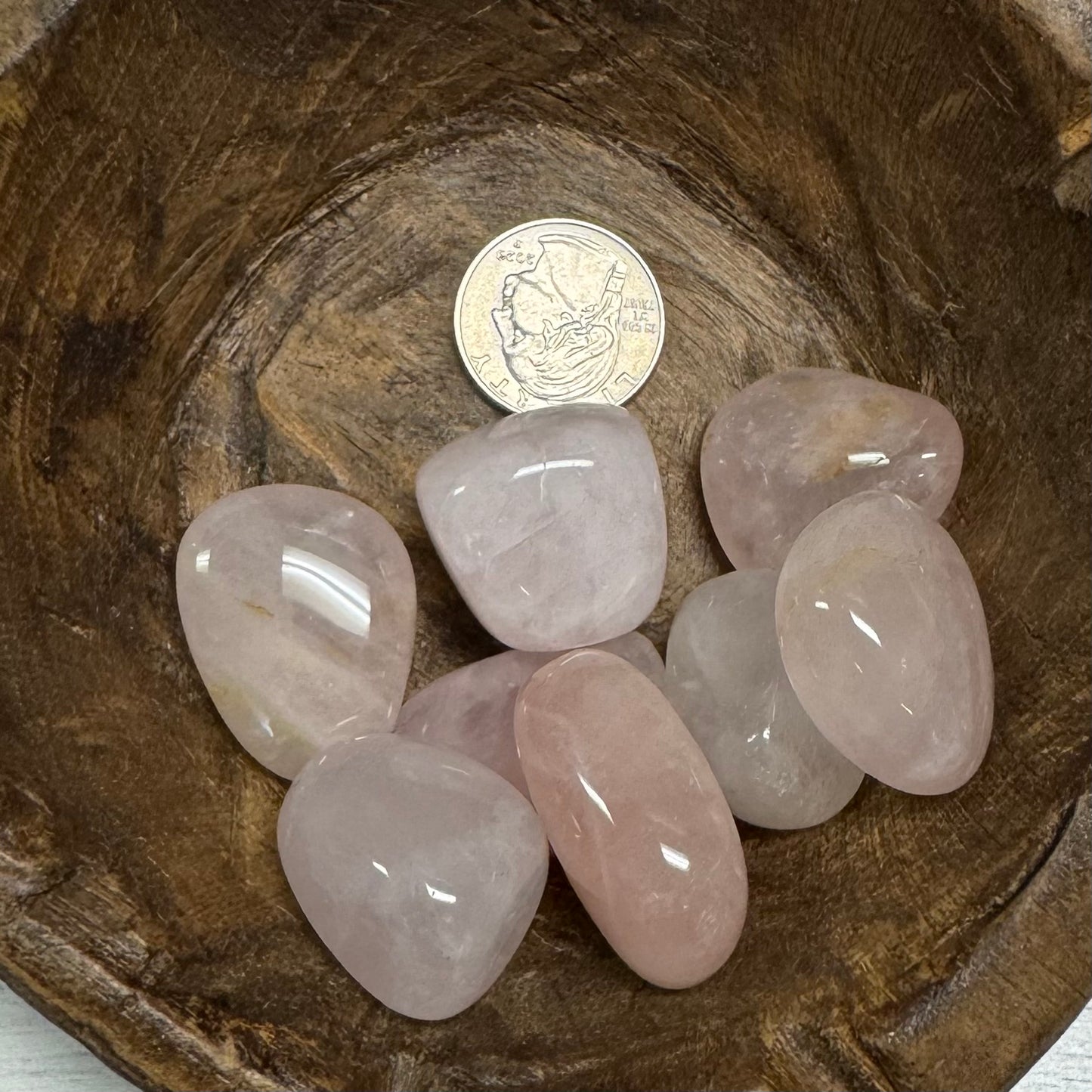 Pink crystals on a wooden surface with a coin for scale