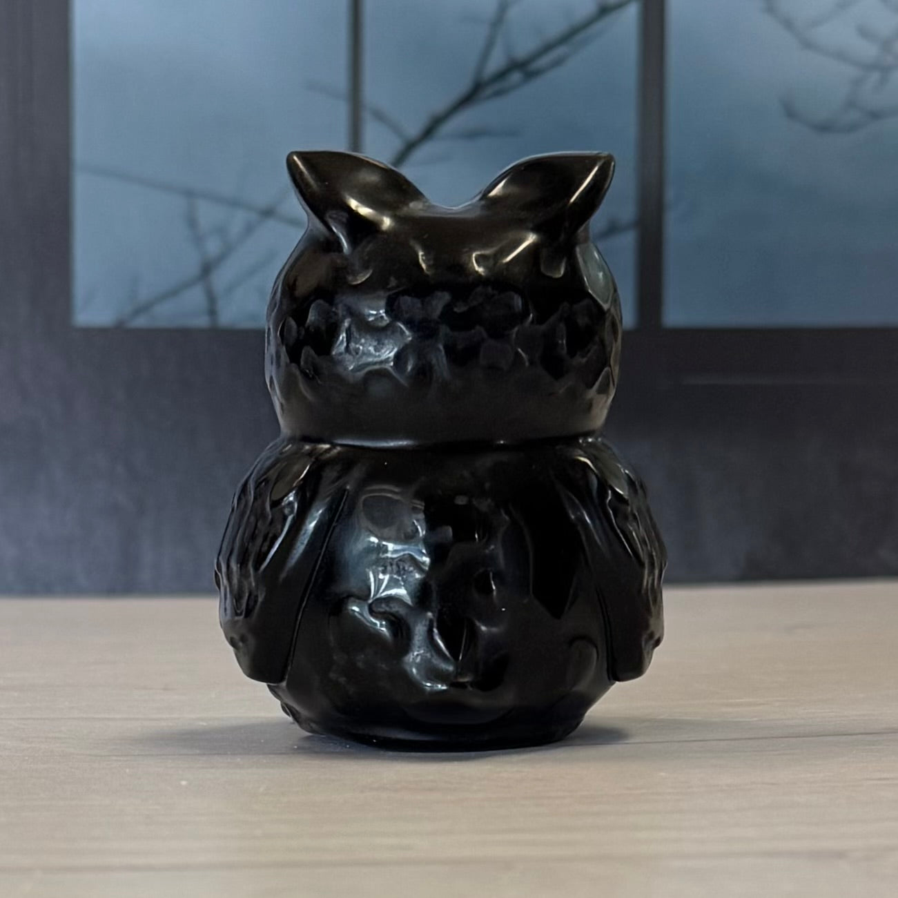 Black ceramic cat-shaped object on a wooden surface with a blurred background