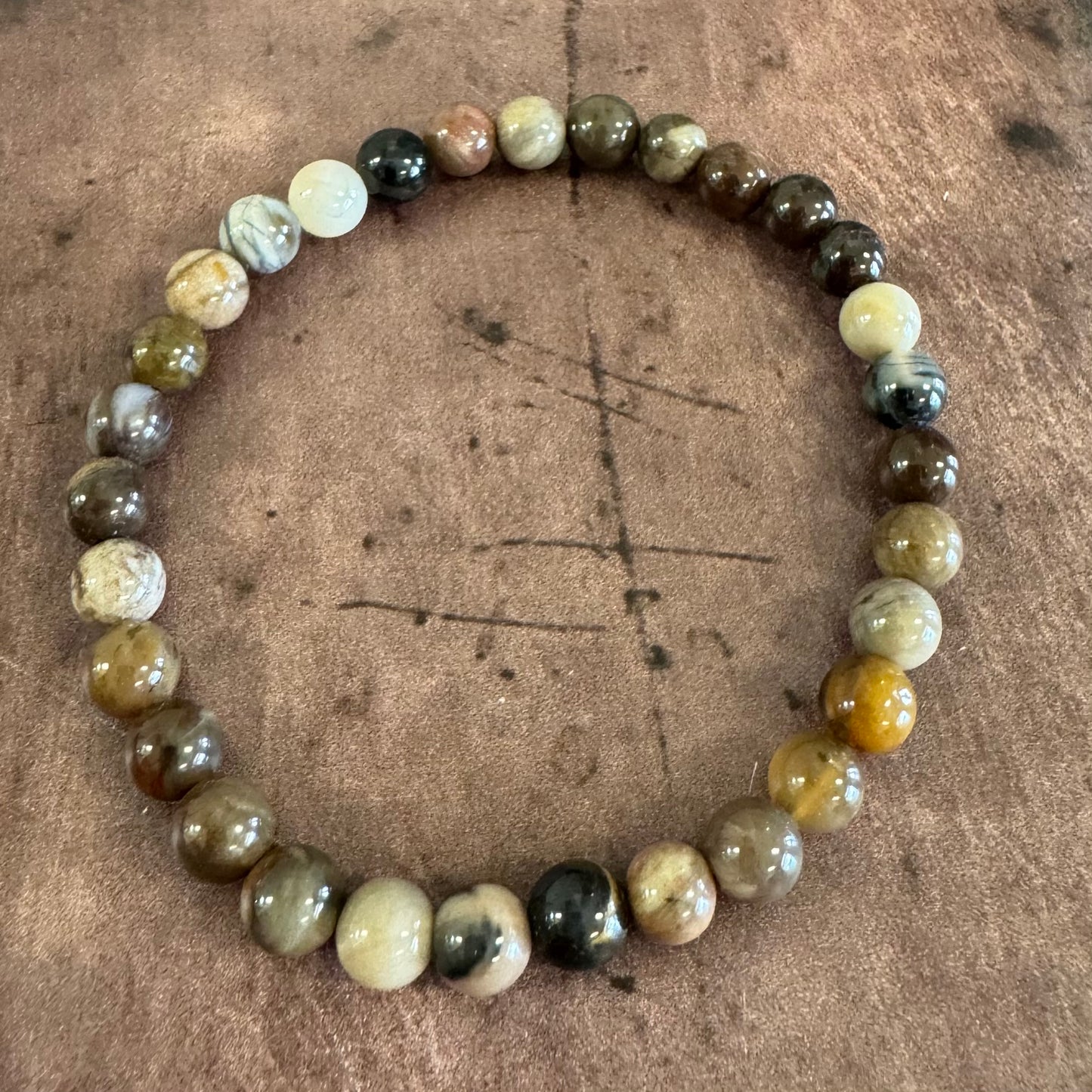 Round beaded bracelet with multicolored stones on a brown surface
