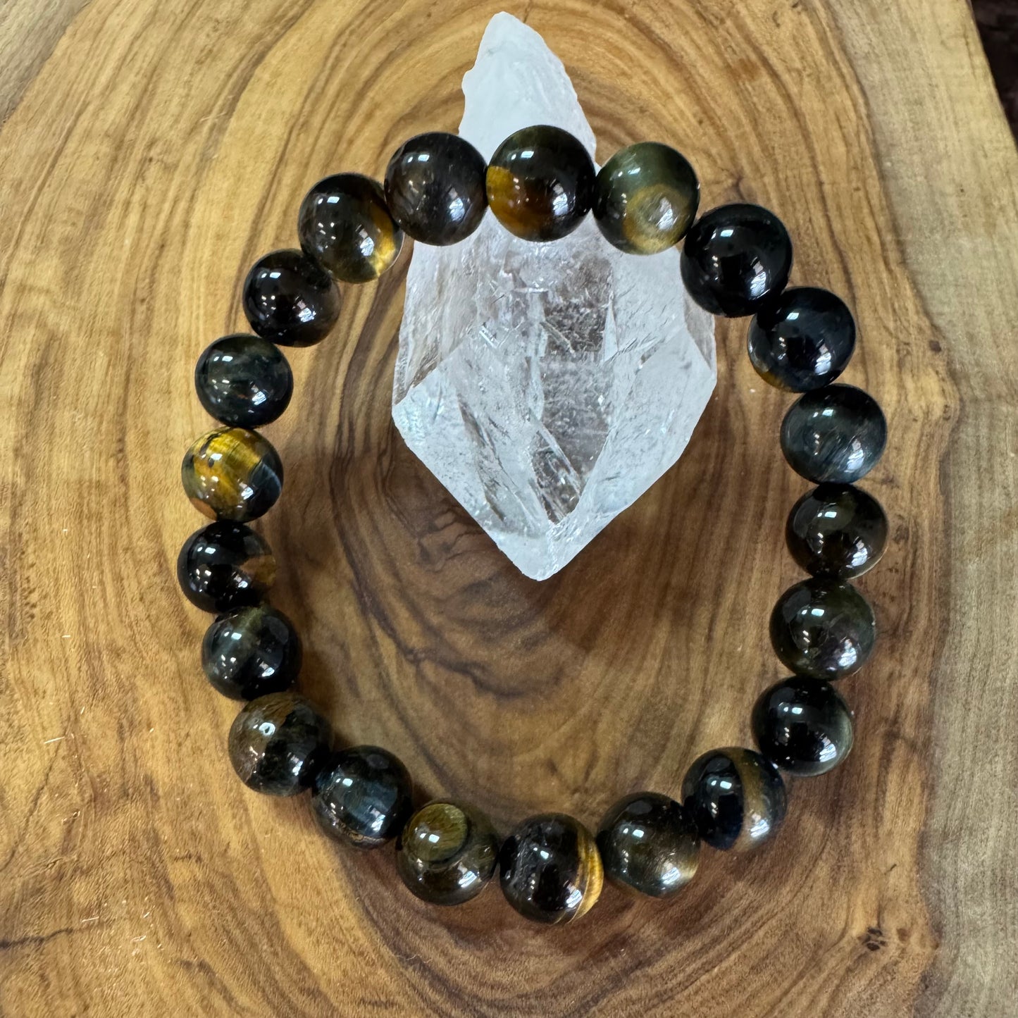 blue tiger's eye beaded bracelet on a wooden surface with a crystal
