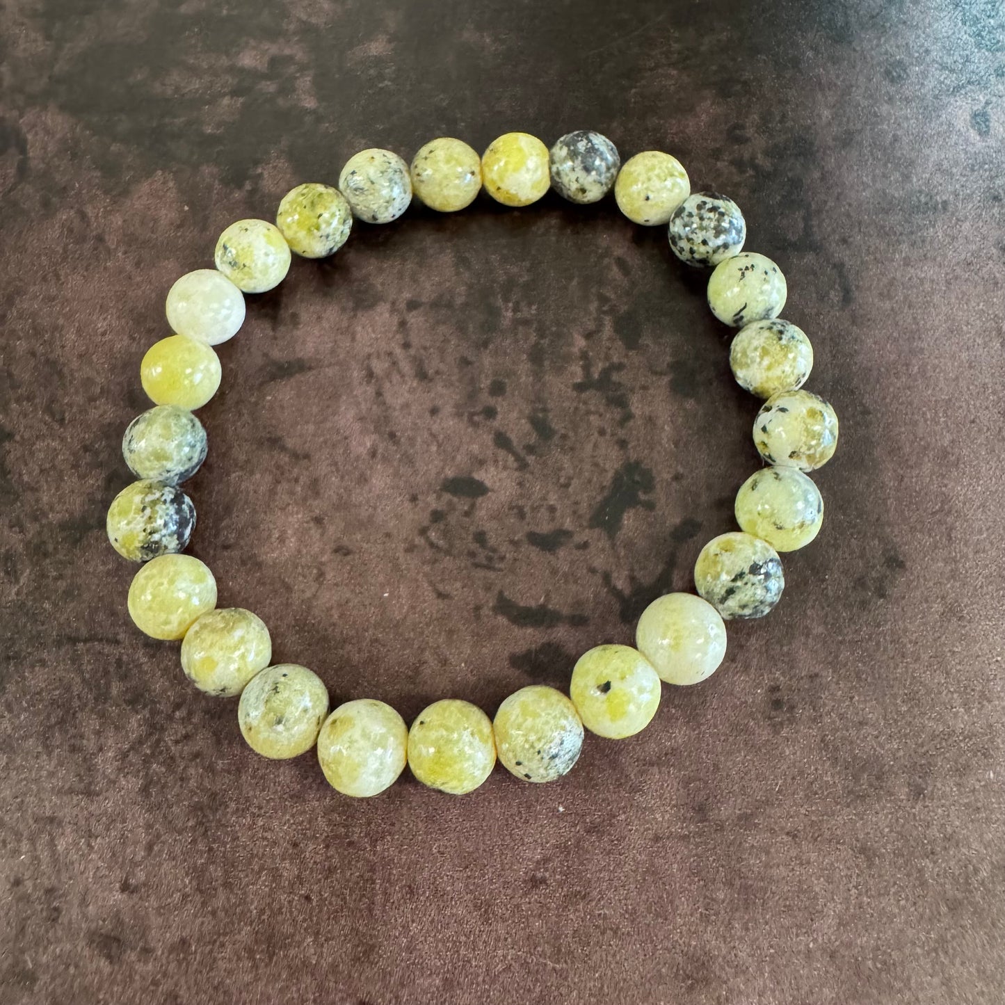 Round beaded bracelet with yellow and gray stones on a brown surface