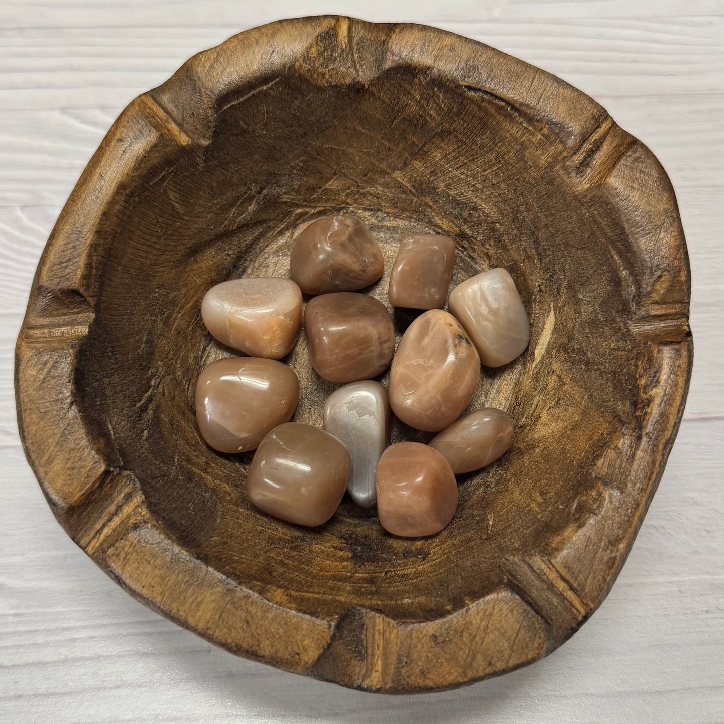 Wooden bowl with stones on a light wooden surface