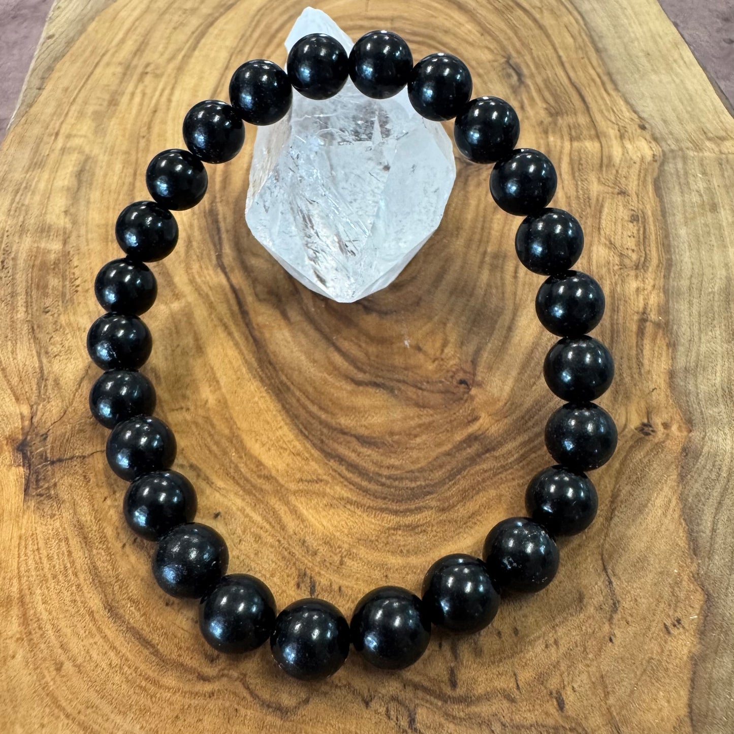 Black beaded bracelet on a wooden surface with a crystal rock