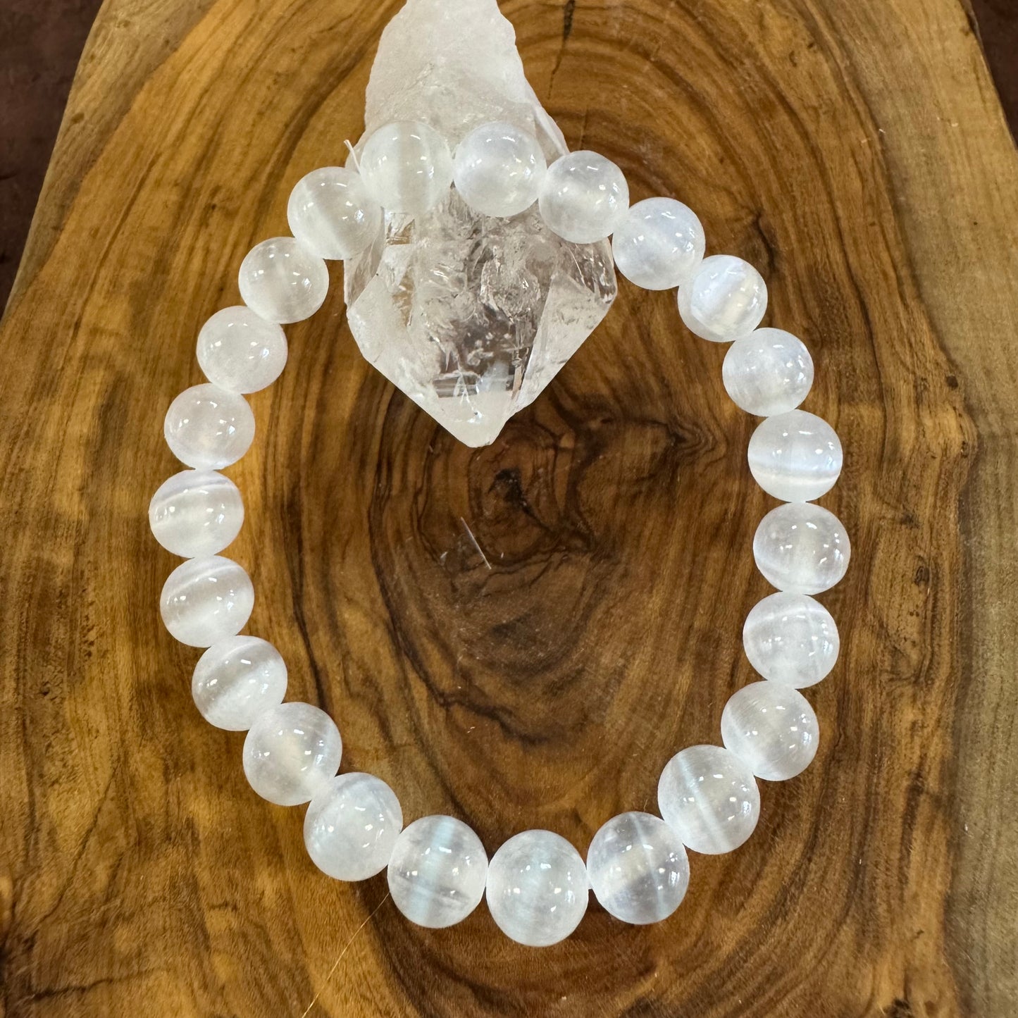 White beaded bracelet on a wooden surface with a crystal