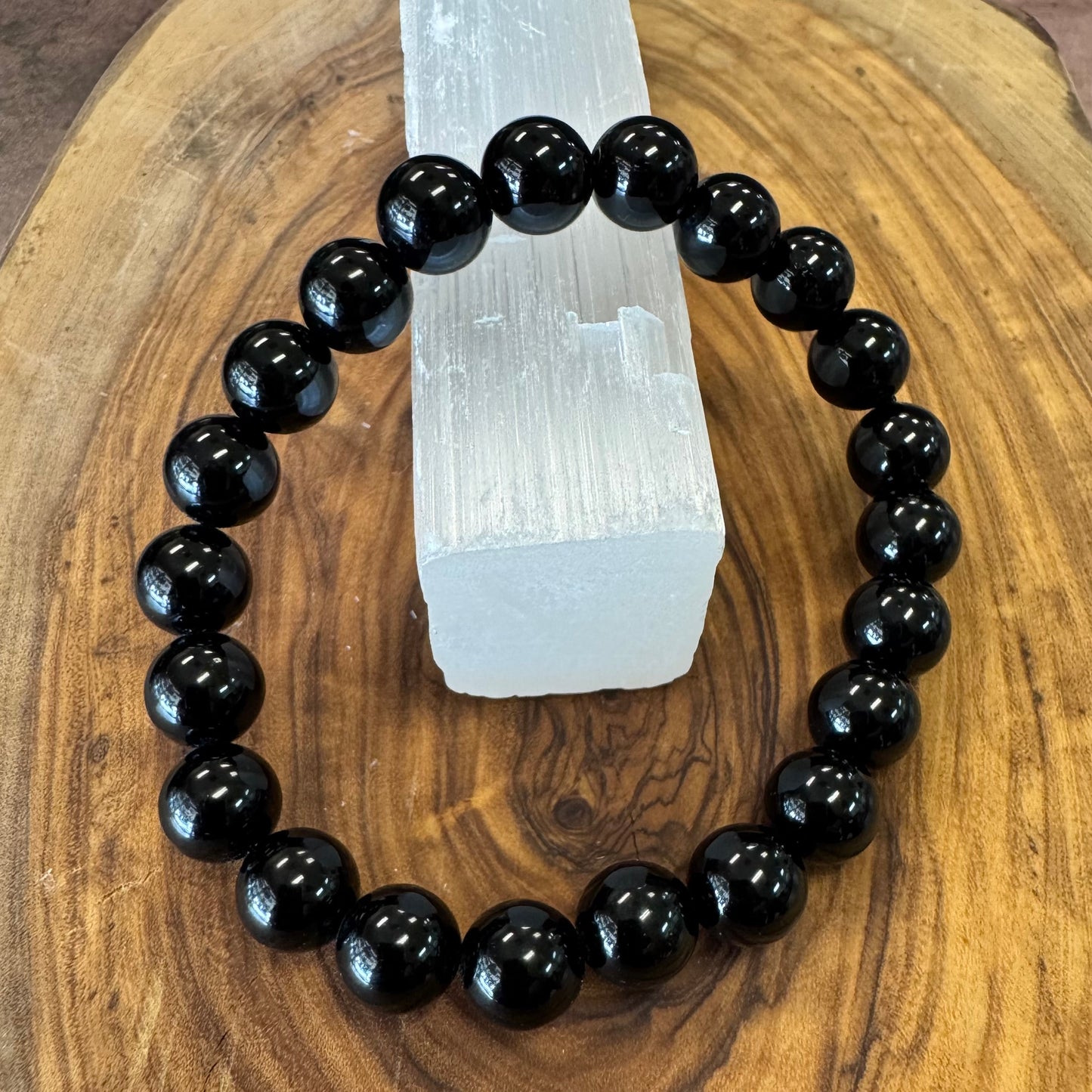 Black beaded bracelet on a wooden surface with a crystal