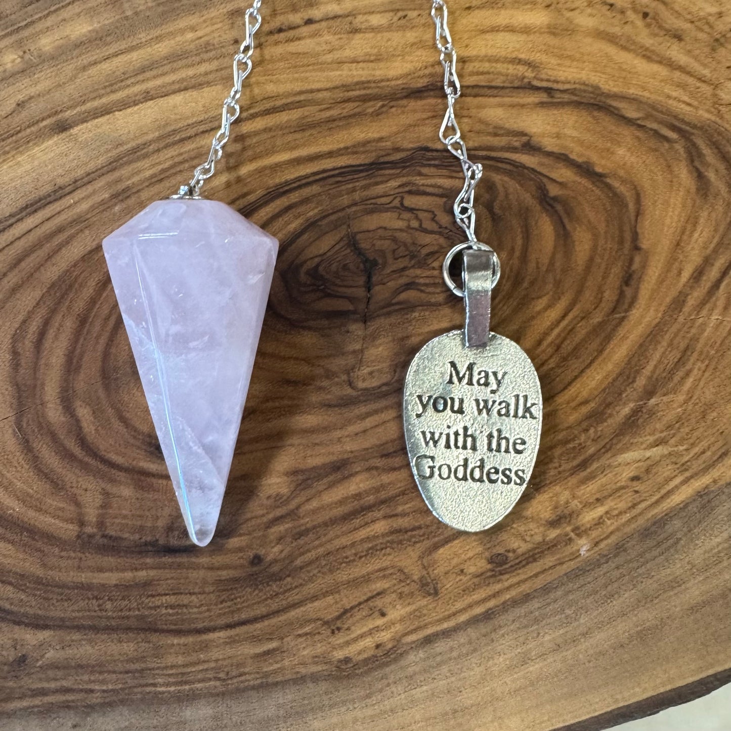 Necklace with a crystal pendant and an engraved metal tag on a wooden surface