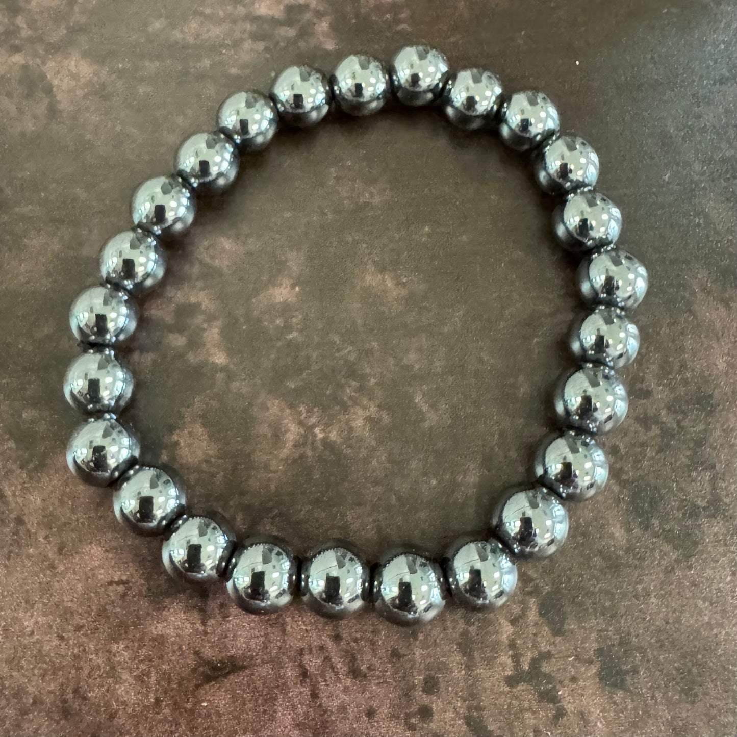 Silver beaded bracelet on a textured brown surface