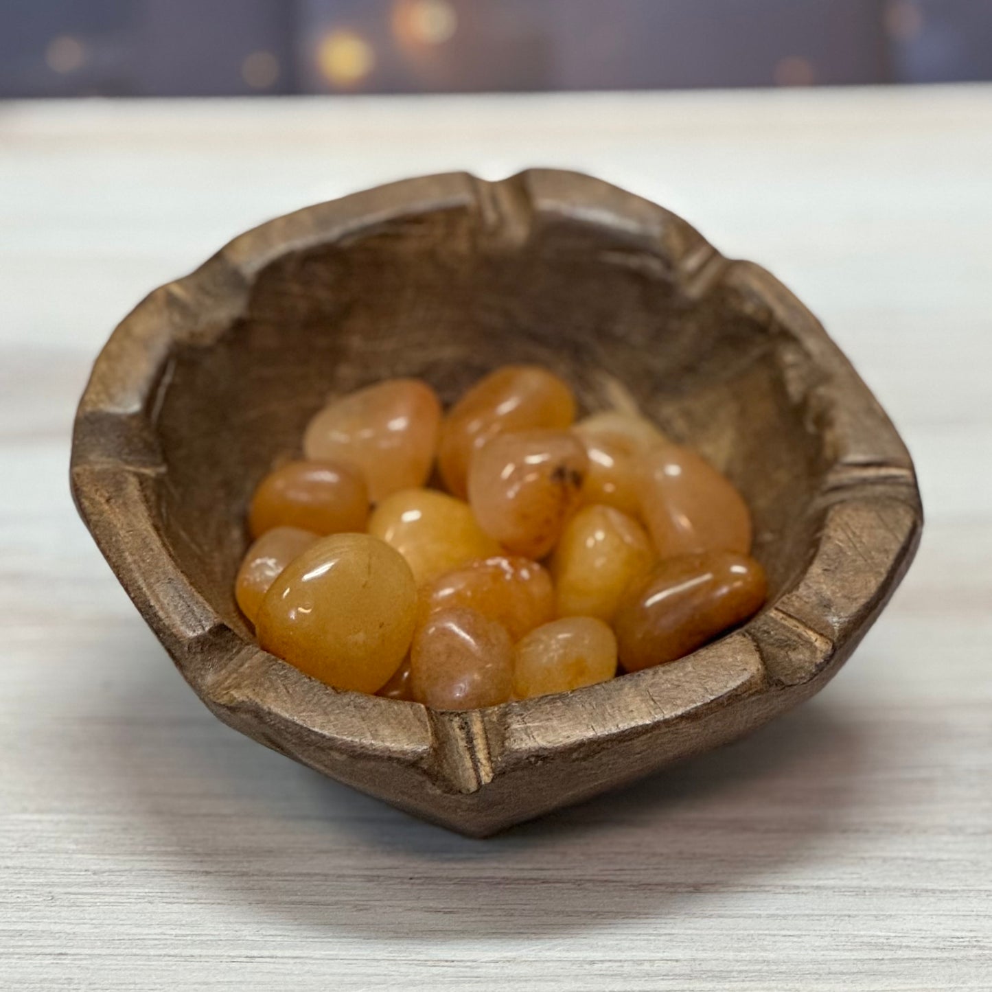 A collection of Golden Azeztulite tumbled stones displayed in a wooden bowl.