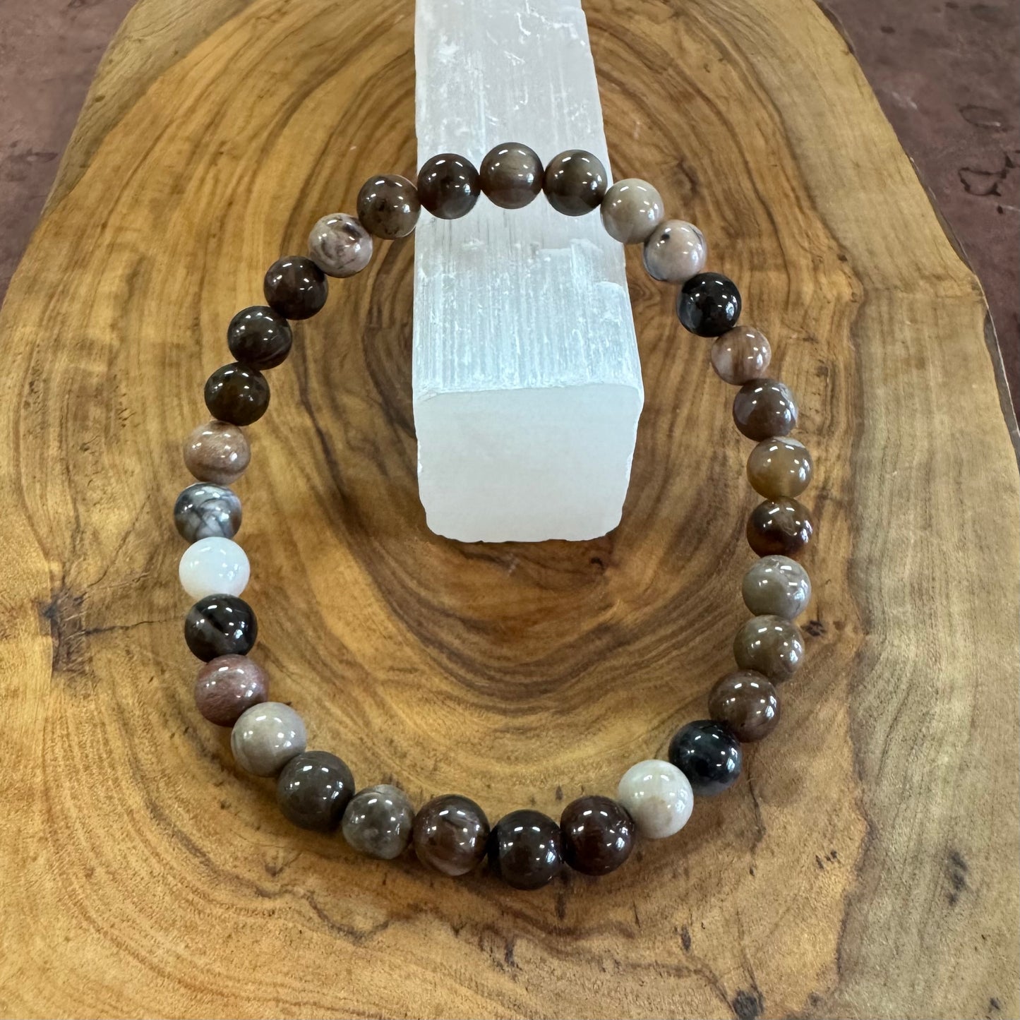 Beaded bracelet on a wooden surface with a crystal in the background
