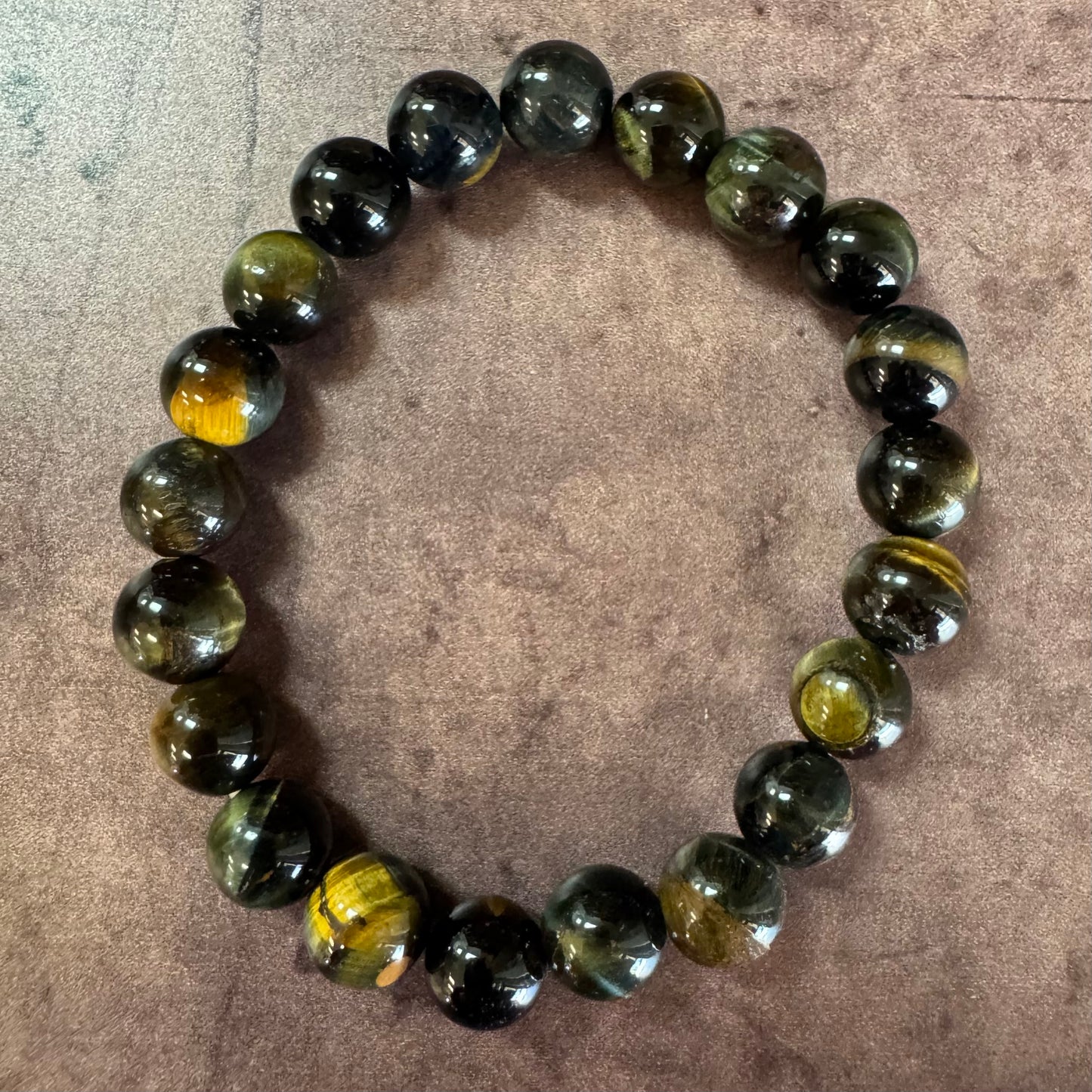 Beaded bracelet with green and black stones on a textured surface