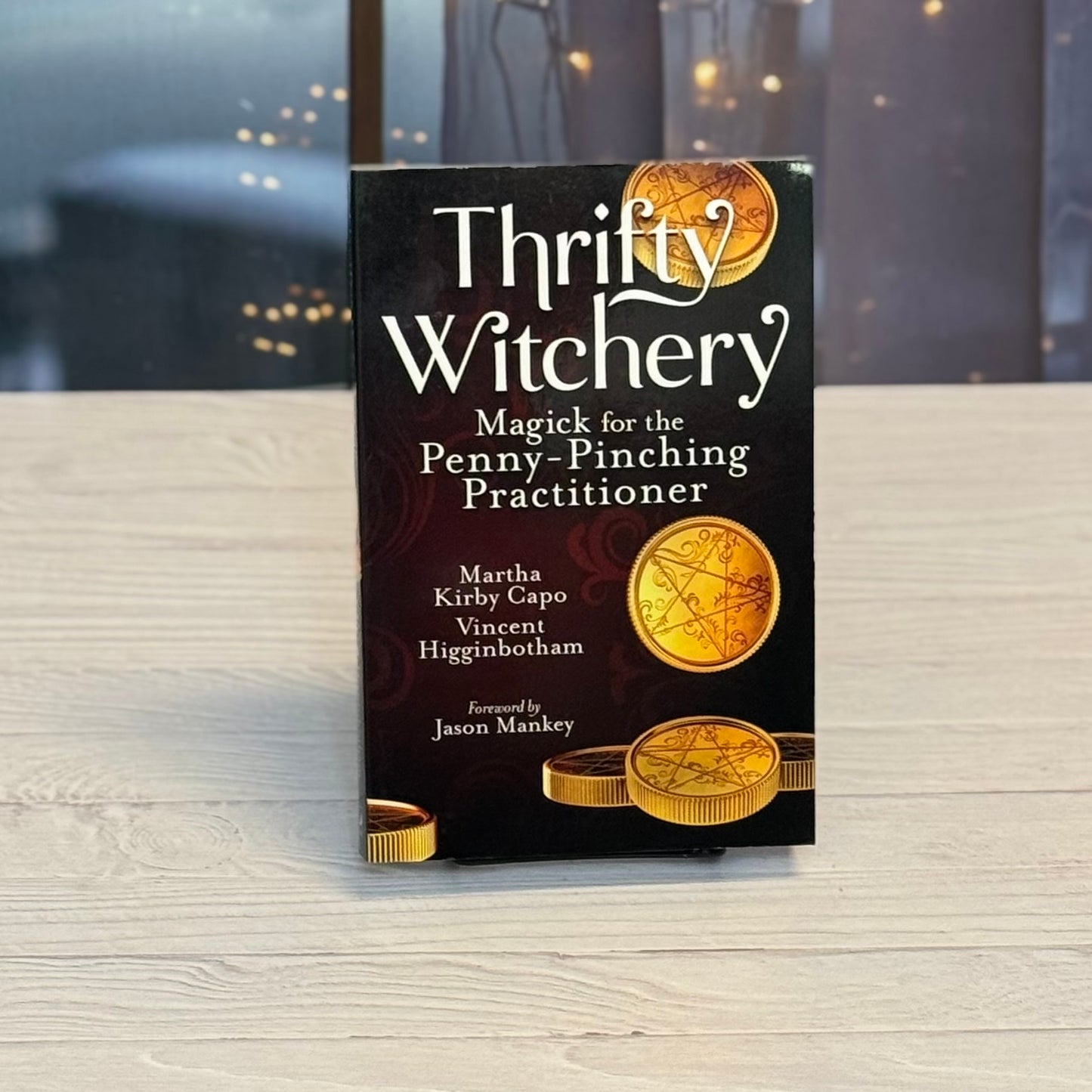 Book titled 'Thrifty Witchery' on a wooden surface with blurred background