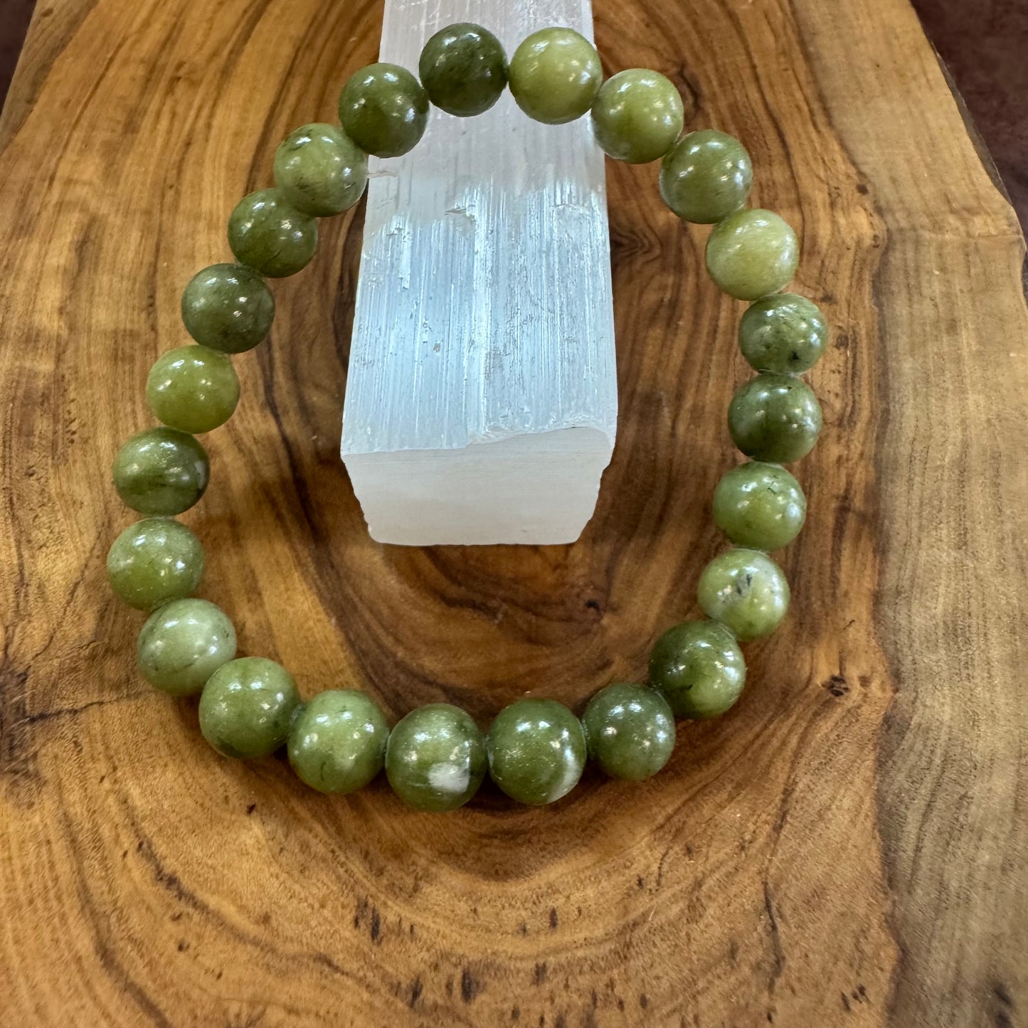Green beaded bracelet on a wooden surface with a crystal
