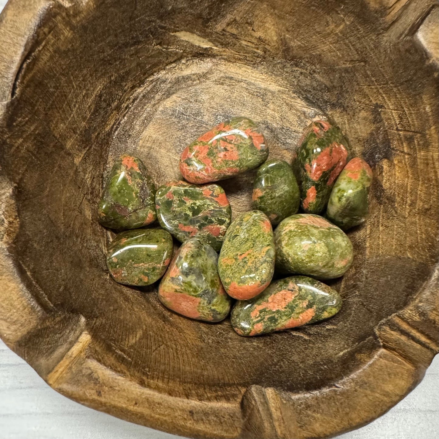 Green and red stones in a wooden bowl