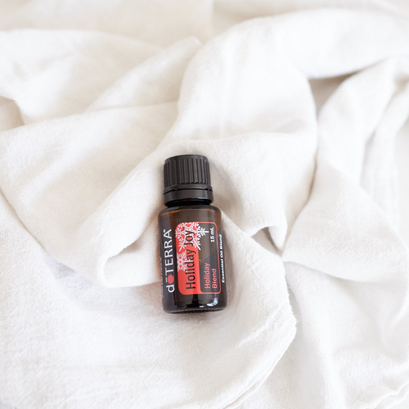 DoTERRA Red Cedar essential oil bottle on a white fabric background