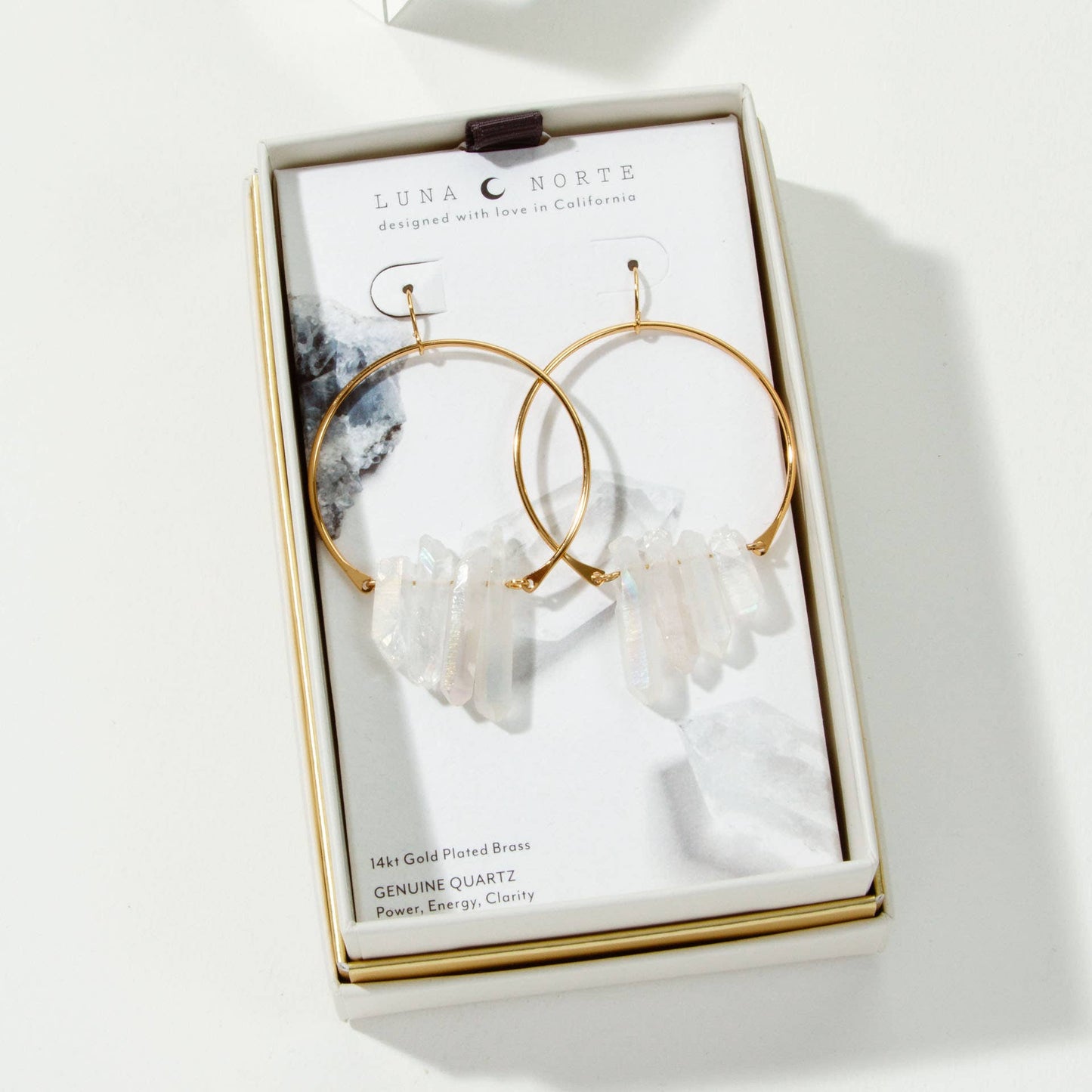Gold hoop earrings with crystal elements on a branded card in a box