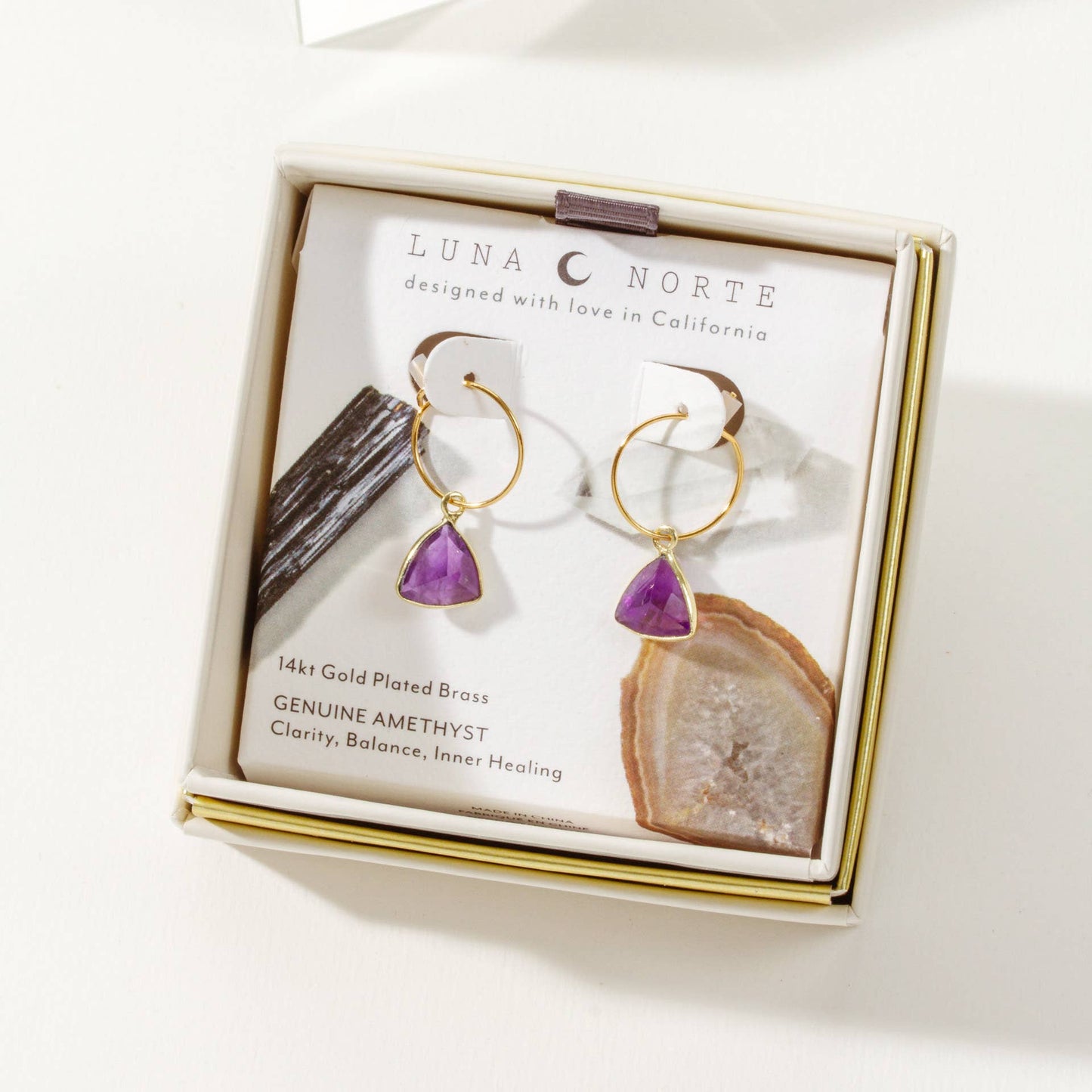 LUNA NORTE earrings with purple gemstones in a branded box on a white background