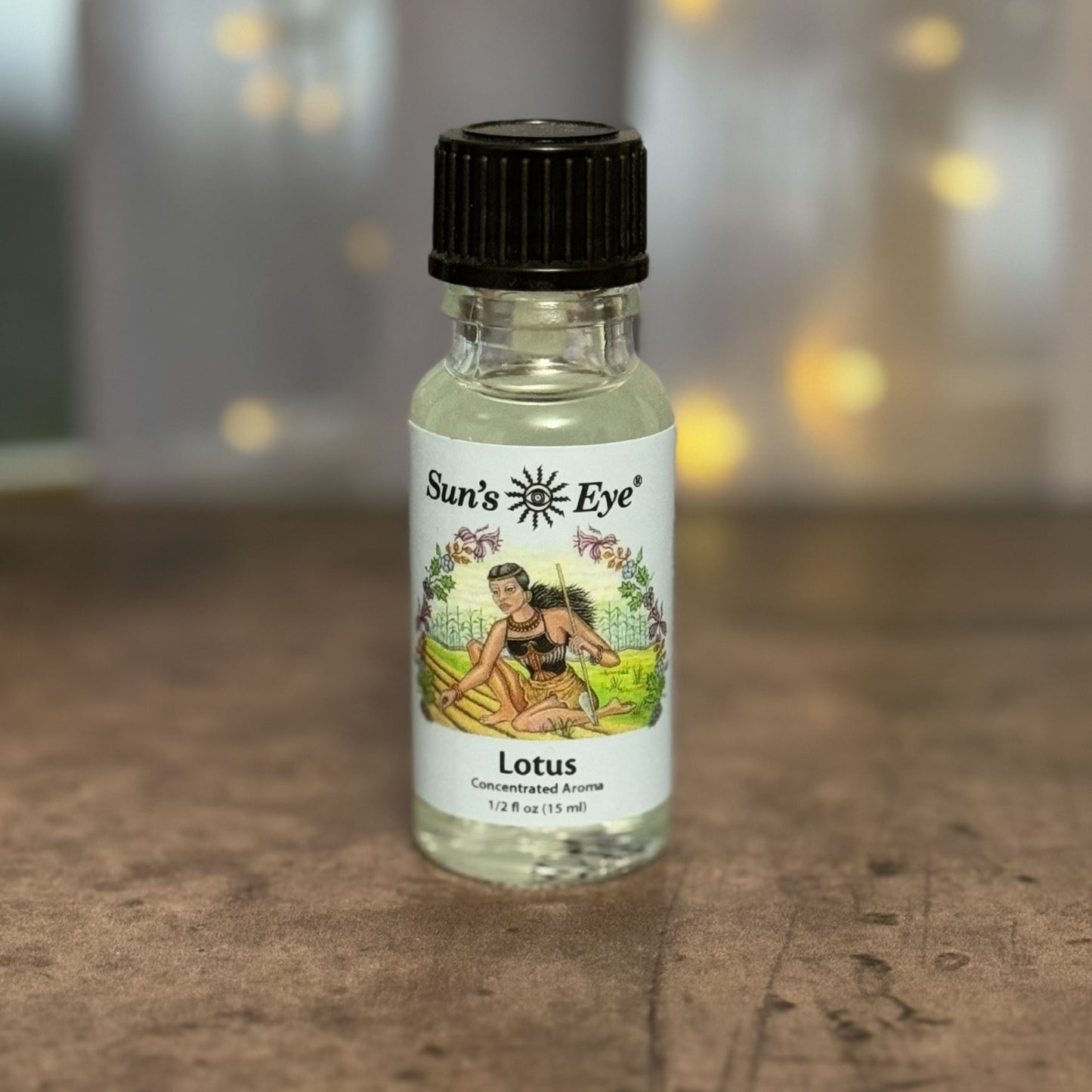 Bottle of Sun's Eye Lotus concentrated aroma on a wooden surface with a blurred background