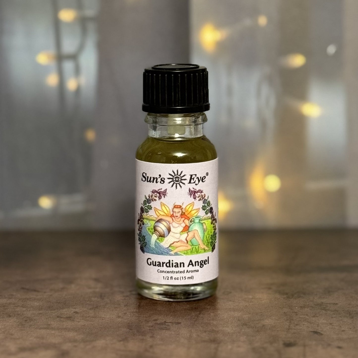 Bottle of Sun's Eye Guardian Angel essential oil on a wooden surface with a blurred background