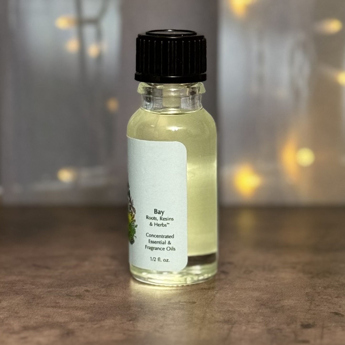 Small bottle of Bay essential oil with a black cap on a wooden surface.