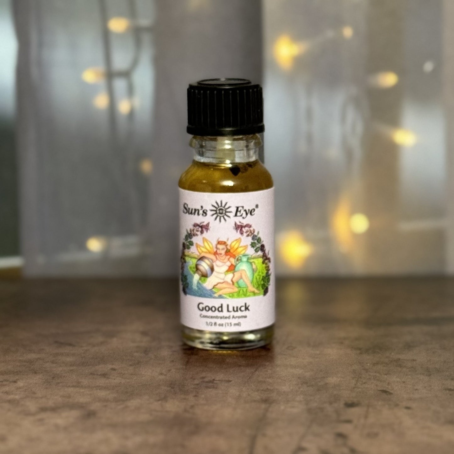 Bottle of 'Good Luck' perfume by Sun's Eye on a wooden surface with a blurred background.