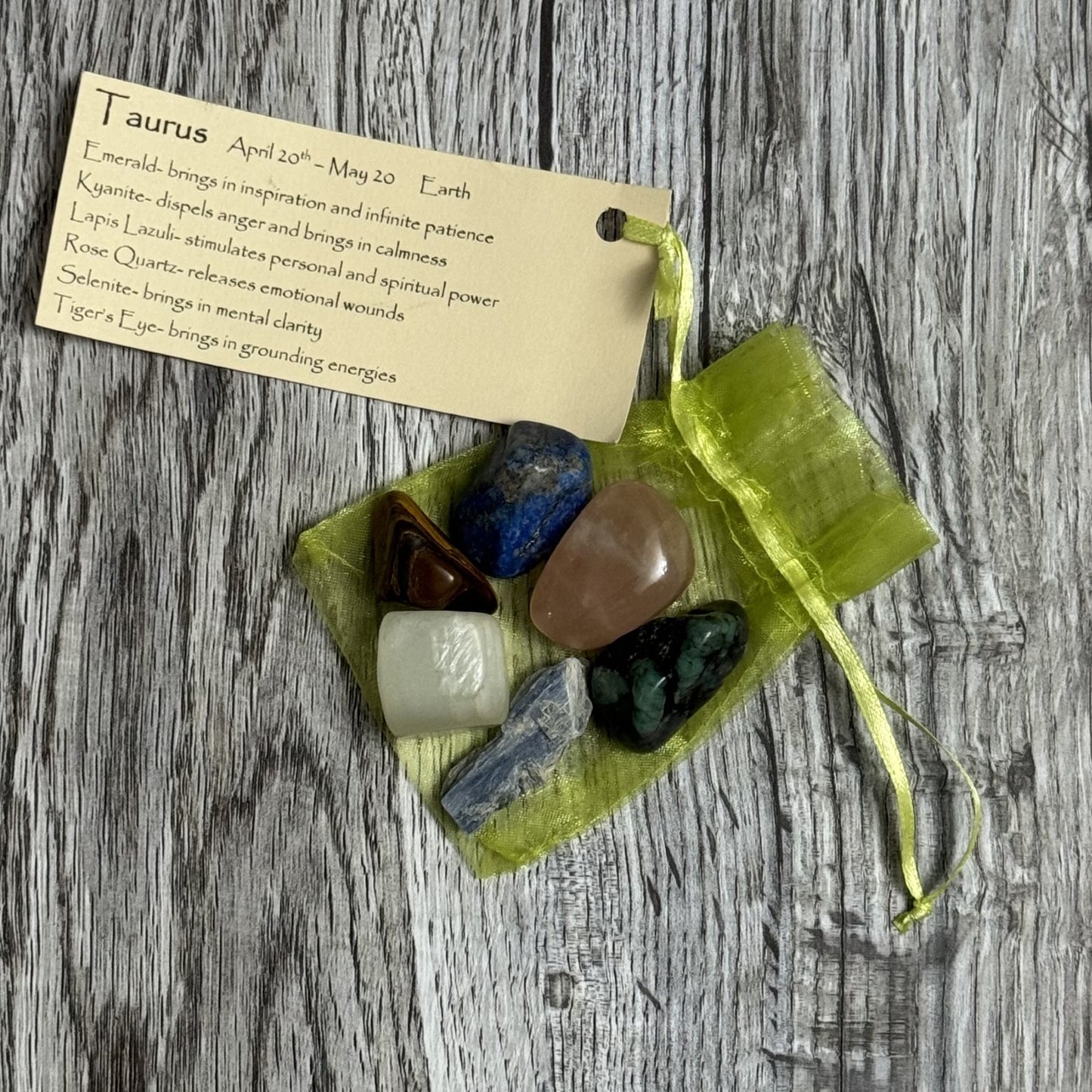 Set of tumbled stones in a green organza bag with a card on a wooden surface