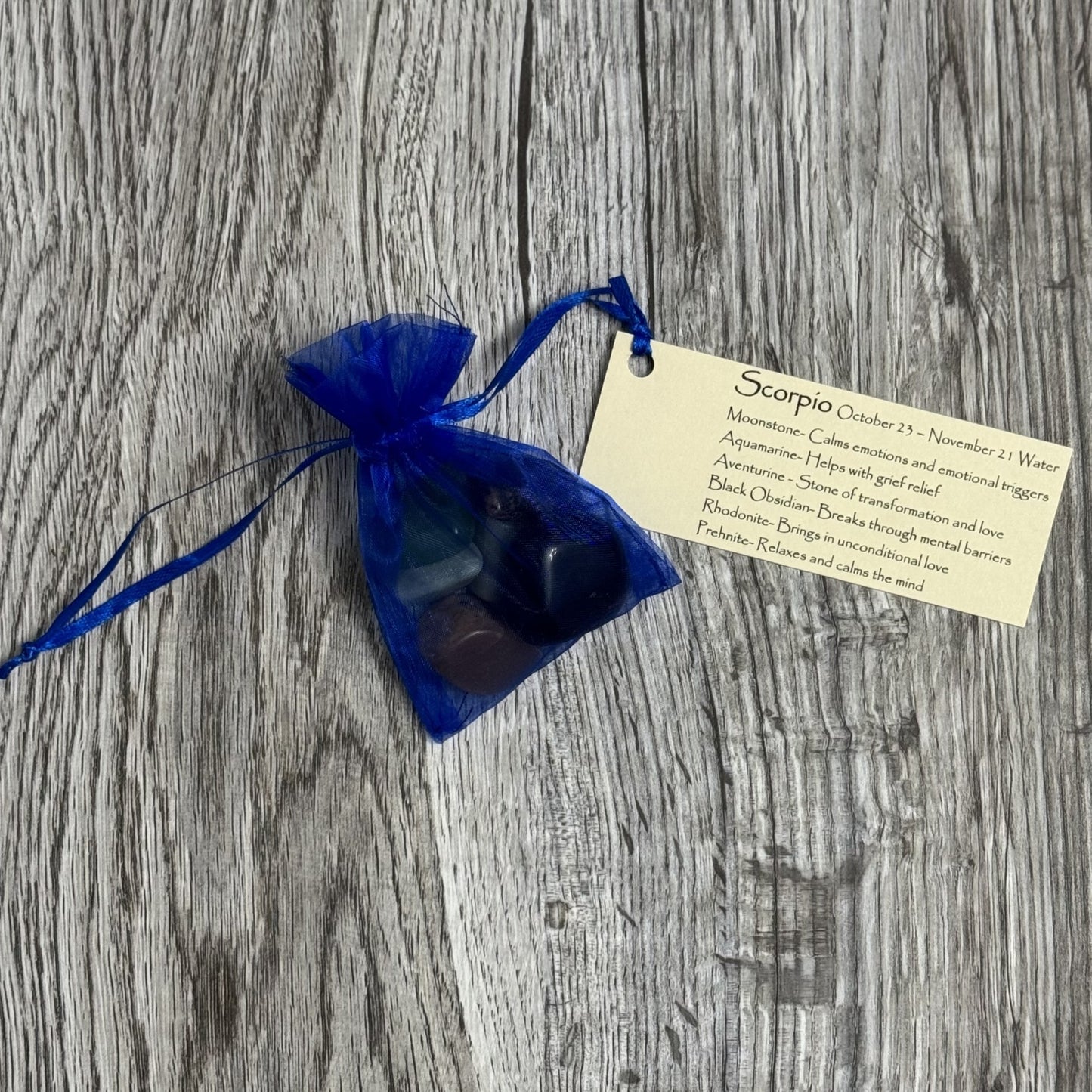 Blue drawstring bag with black stones and a tag on a wooden surface