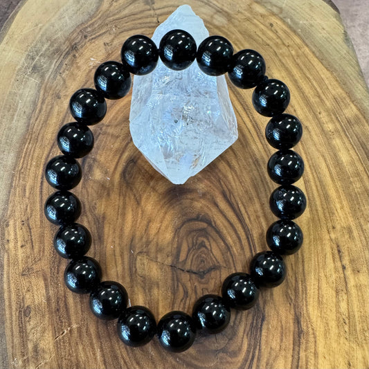 Black beaded bracelet on a wooden surface with a crystal