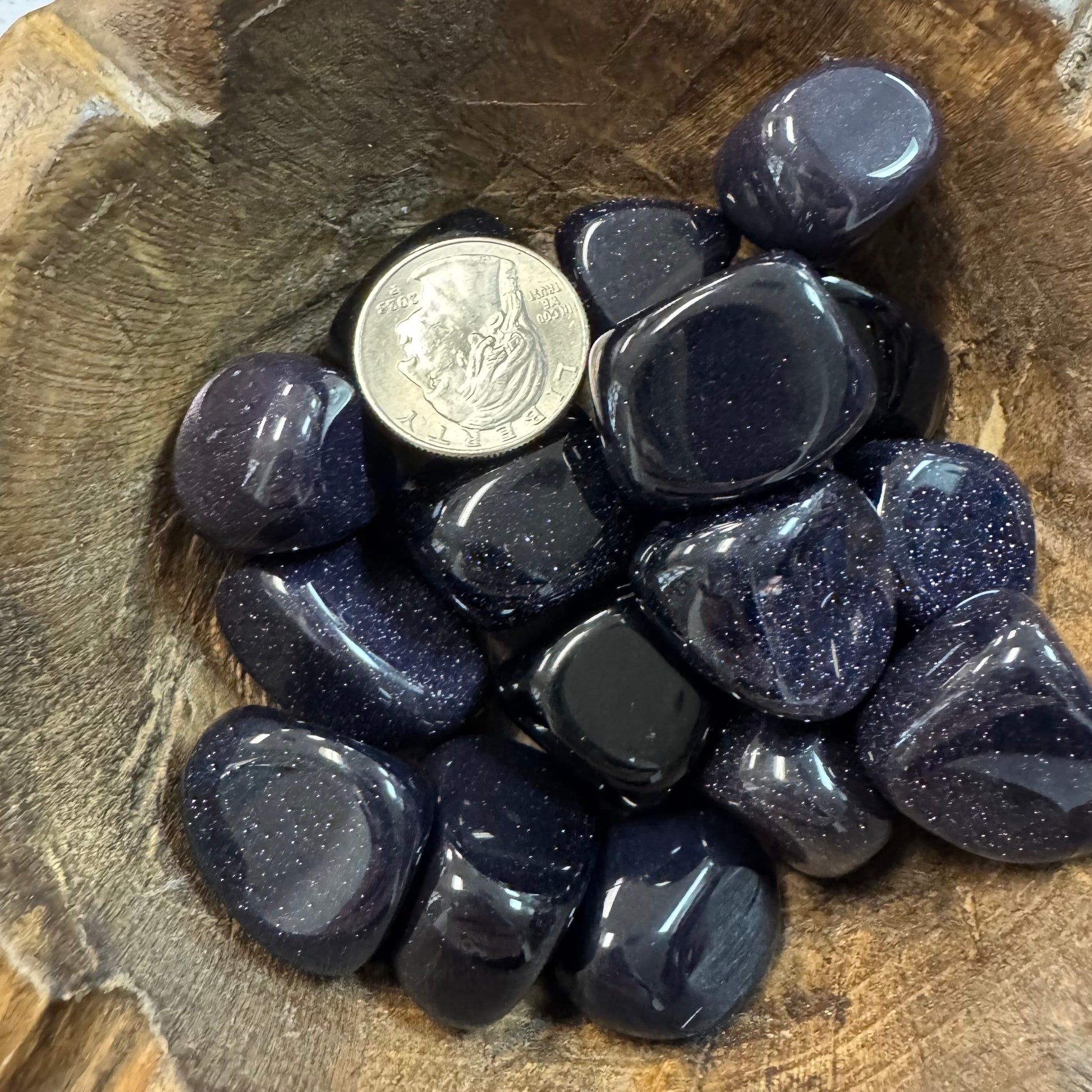 Dark blue stones on a wooden surface with a coin for scale