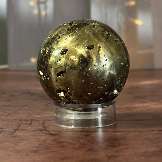 Pyrite crystal sphere on a wooden surface with a blurred background