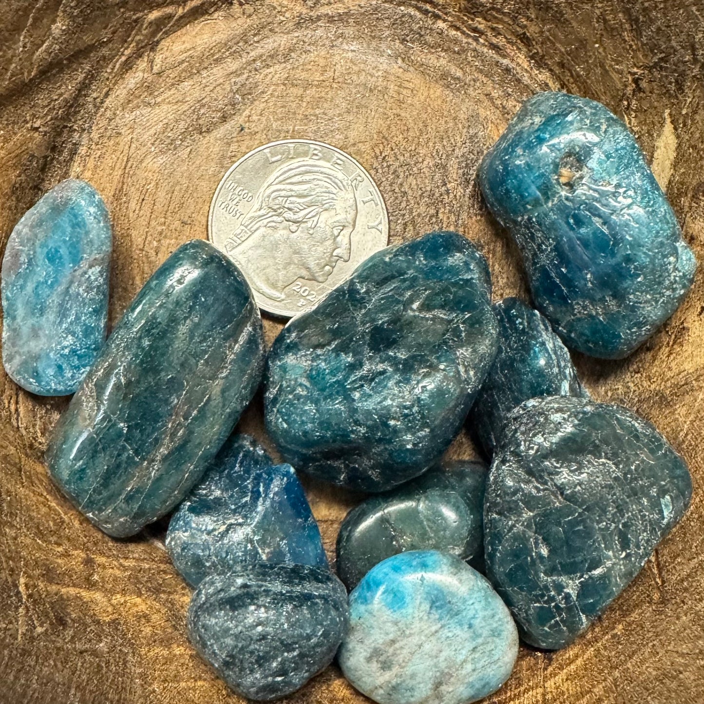 Blue stones on a wooden surface with a coin for scale