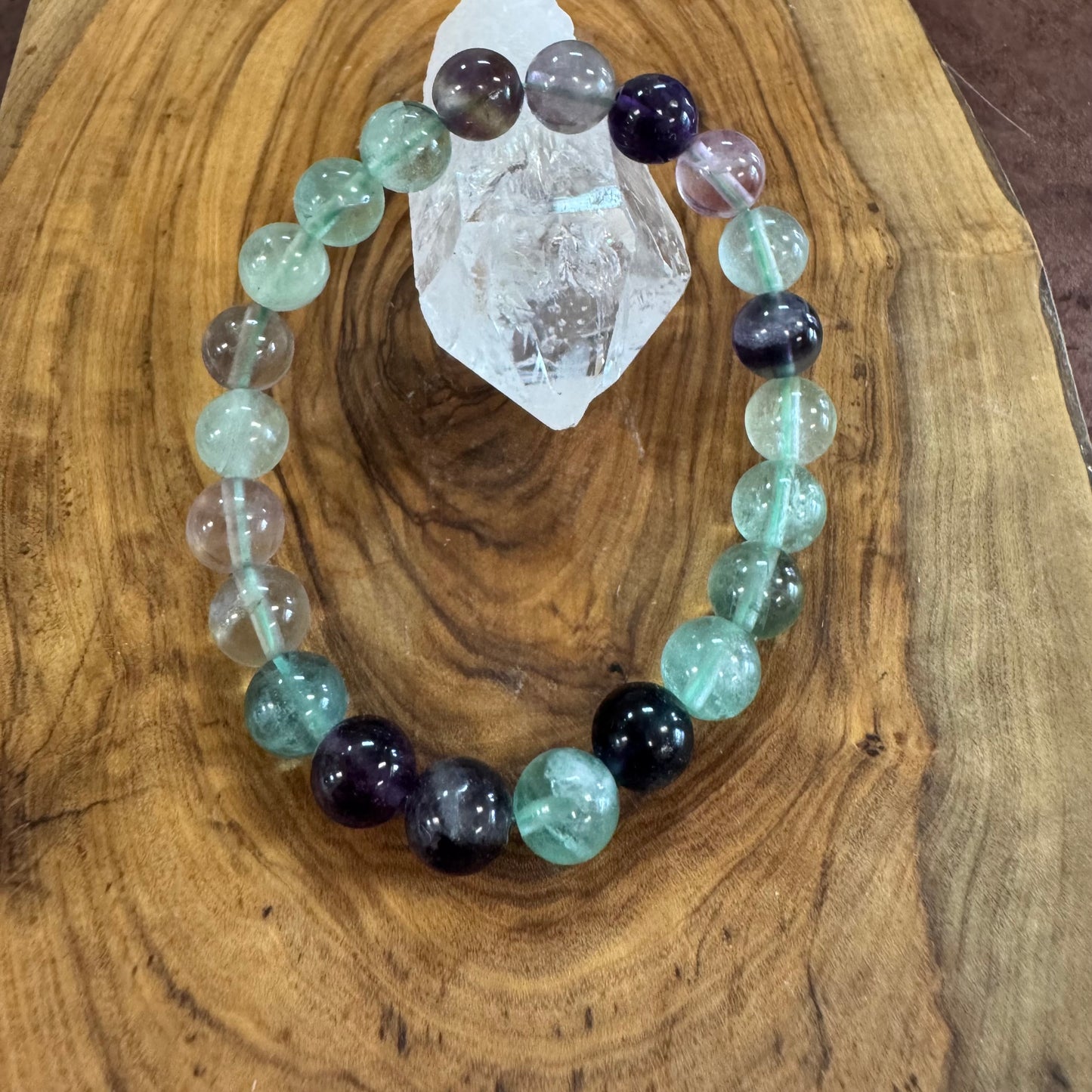 Glowing crystal bracelet on a wooden surface with a crystal rock
