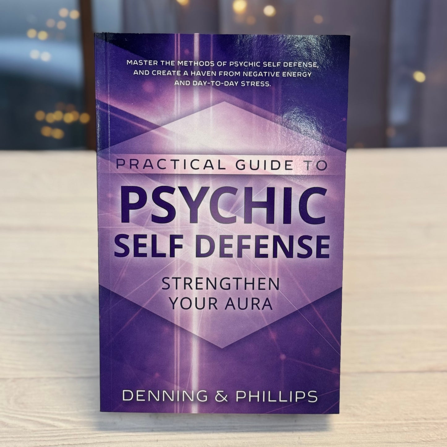 Book titled 'Practical Guide to Psychic Self Defense' by Denning & Phillips on a blurred background