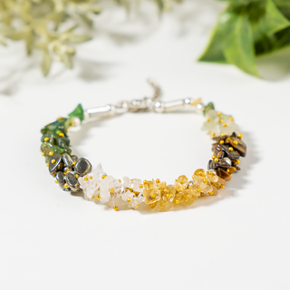 Multicolored beaded bracelet on a white surface with greenery in the background