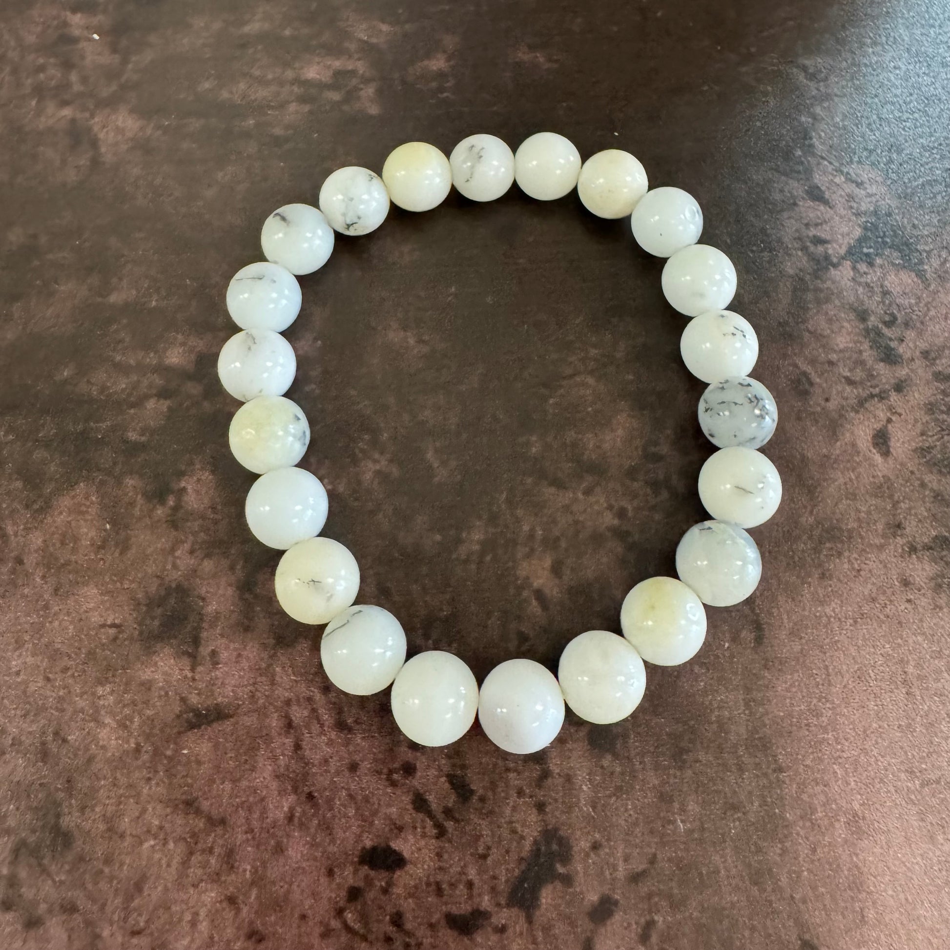 White beaded bracelet on a textured brown surface