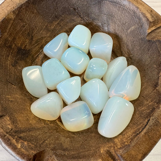Opalite stones in a wooden bowl on a light wooden surface