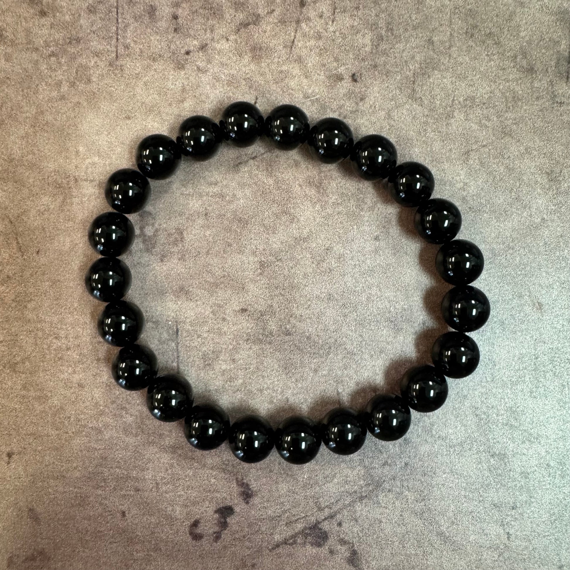 Black beaded bracelet on a textured beige surface