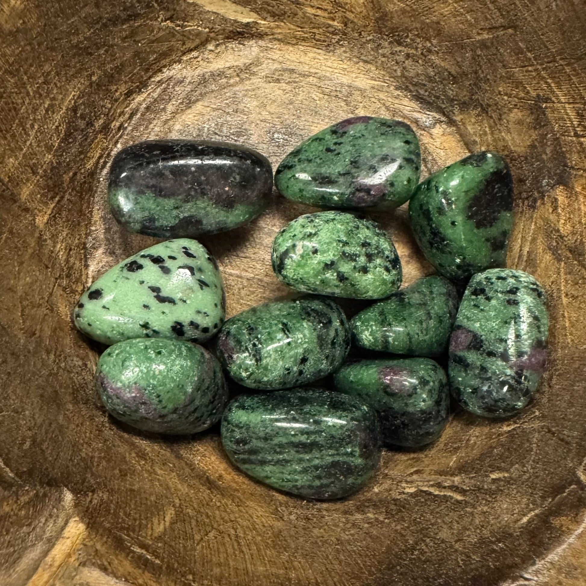 Green and black speckled stones on a wooden surface