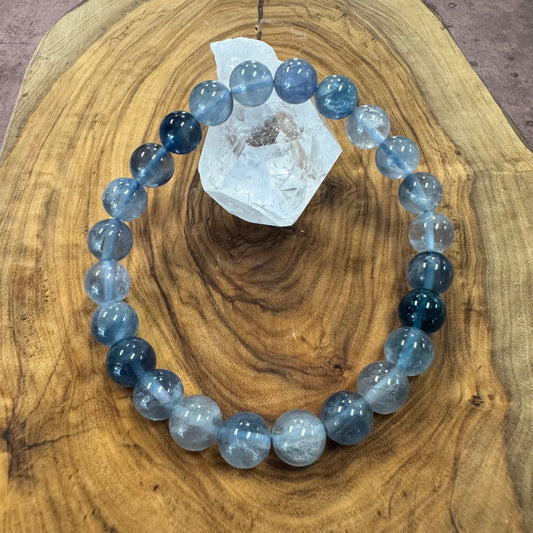Blue and gray beaded bracelet on a wooden surface with a crystal.