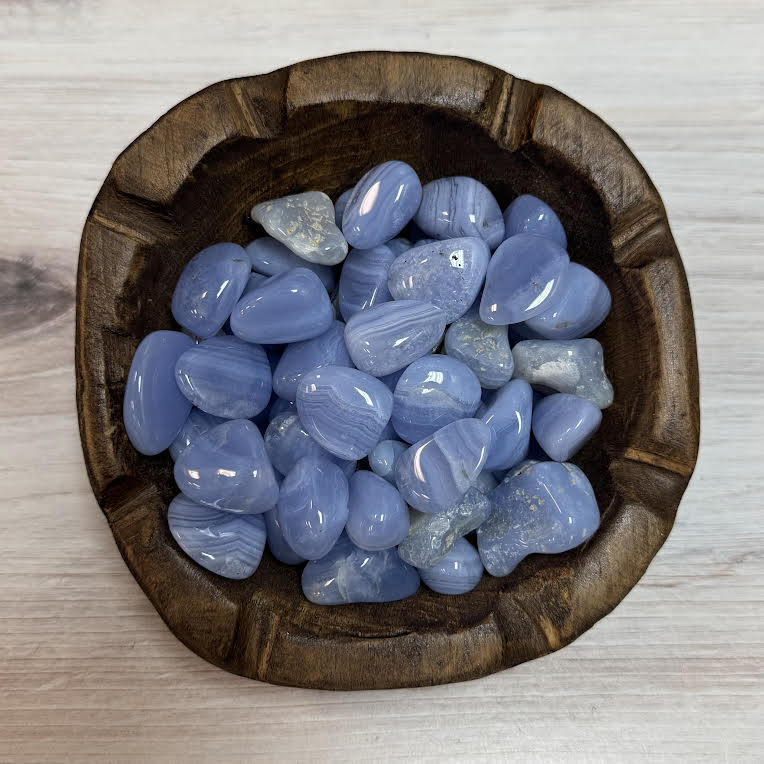 Wooden bowl filled with blue stones on a light wooden surface